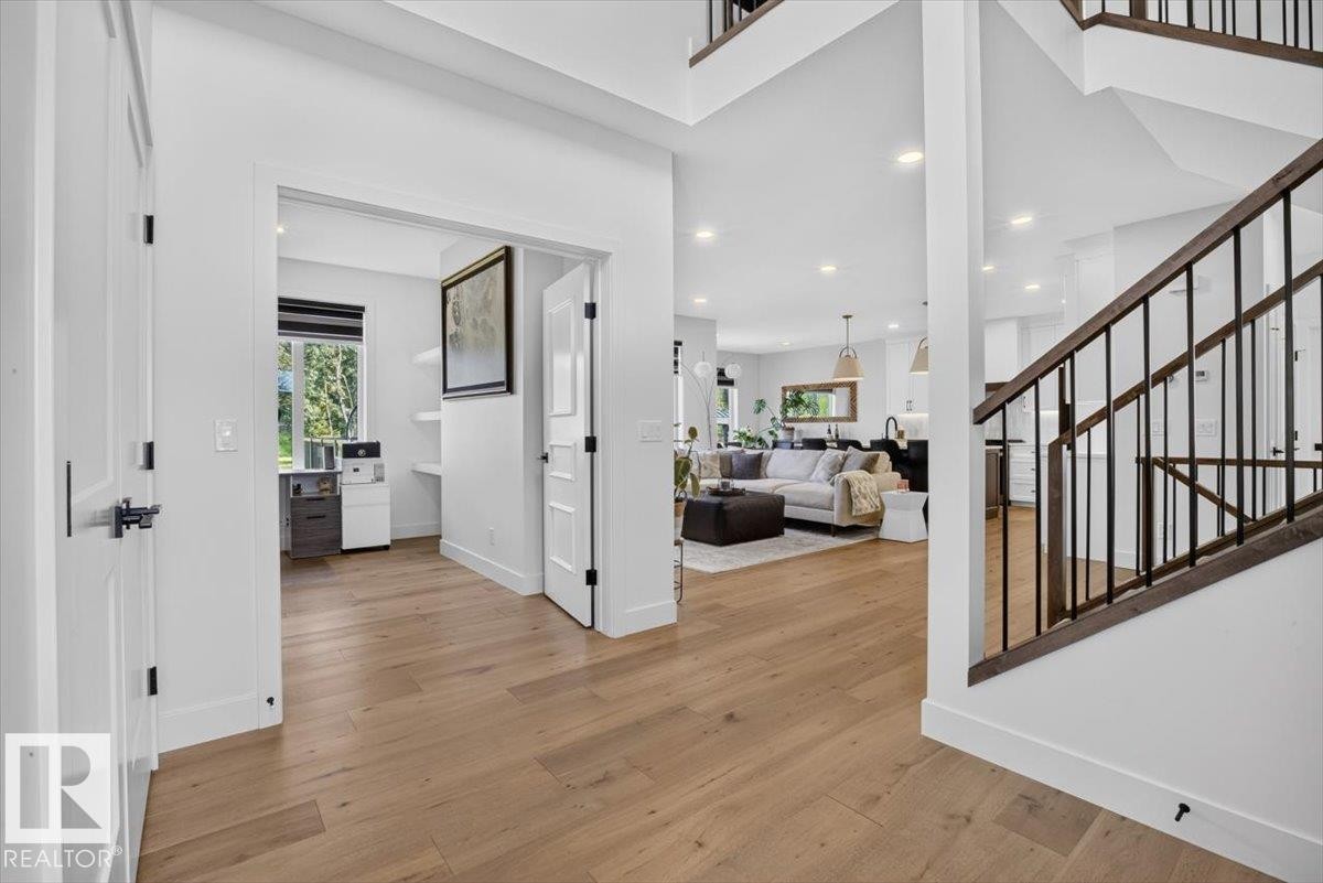 Wood-finish flooring throughout, white walls, and a staircase with dark wood-finish handrails and black metal balusters - 94 Harvest Crescent, Ardrossan, AB - Indoor Photo Showing Other Room