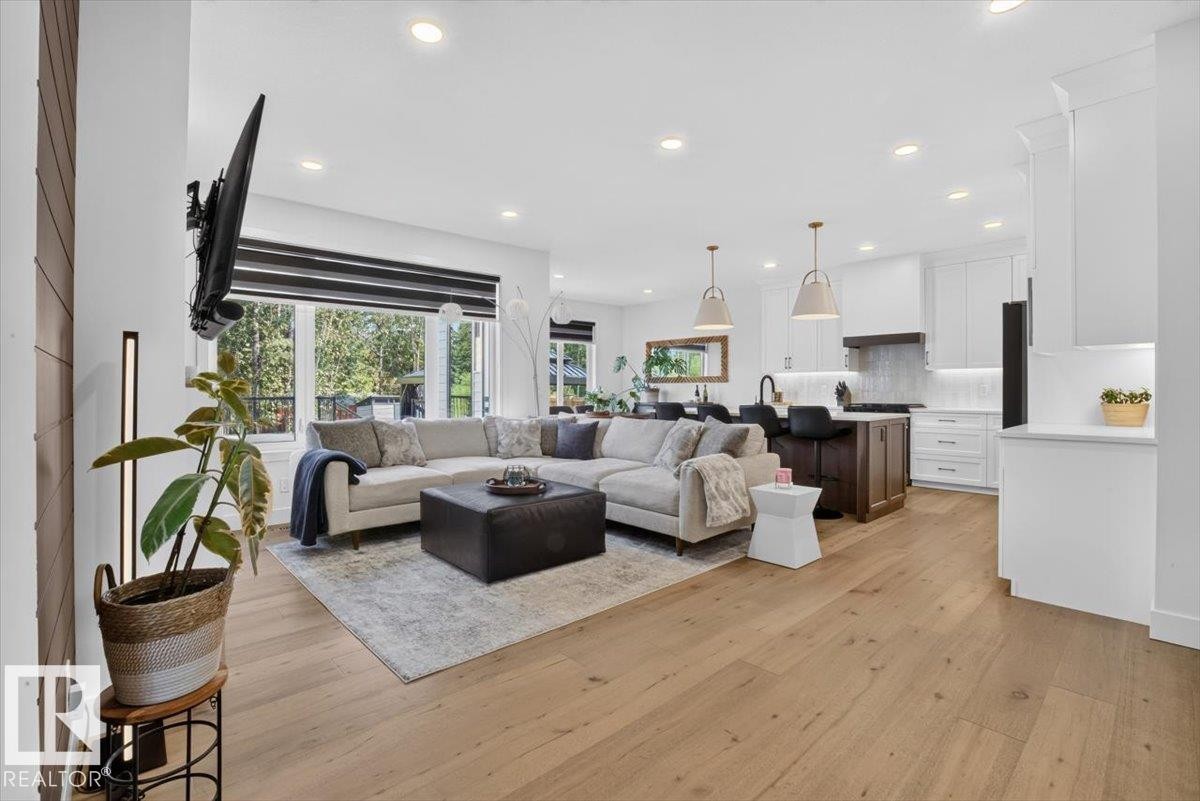 Expansive living area featuring light wood-finish flooring, recessed lighting, and large windows - 94 Harvest Crescent, Ardrossan, AB - Indoor