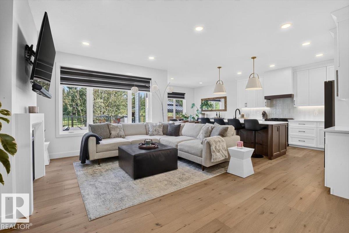 Open-concept living space featuring wood-finish flooring, recessed lighting, and a modern kitchen with a central island and white cabinetry - 94 Harvest Crescent, Ardrossan, AB - Indoor