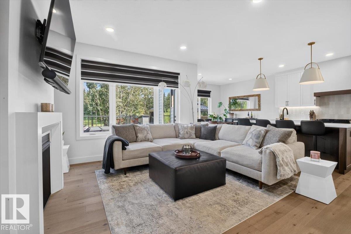Open-concept living space featuring wood-finish flooring, recessed lighting, and a white fireplace - 94 Harvest Crescent, Ardrossan, AB - Indoor Photo Showing Living Room With Fireplace