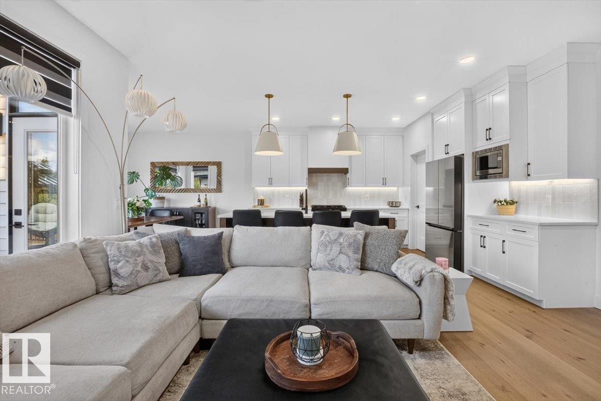 Open-concept living area with wood-finish flooring, white cabinetry, stainless steel appliances, and recessed lighting - 94 Harvest Crescent, Ardrossan, AB - Indoor Photo Showing Living Room
