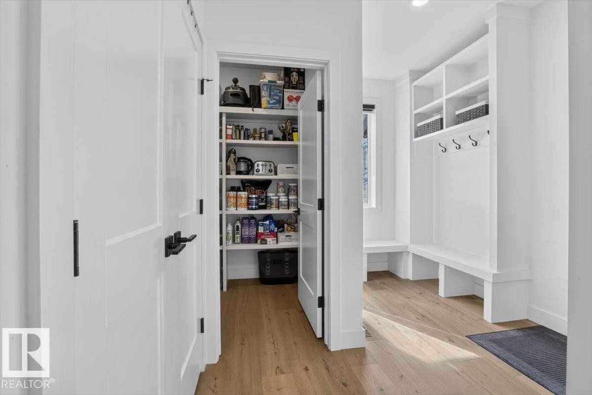 White built-in shelving, integrated bench seating, and wood-finish flooring - 94 Harvest Crescent, Ardrossan, AB - Indoor Photo Showing Other Room