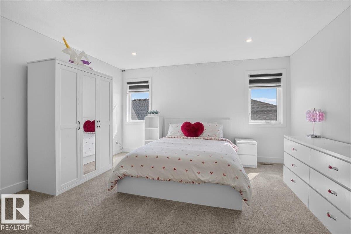 Recessed lighting illuminates the space, featuring two windows with roller blinds, and neutral carpeting throughout - 94 Harvest Crescent, Ardrossan, AB - Indoor Photo Showing Bedroom
