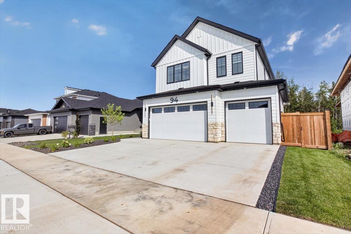 Contemporary exterior with vertical white siding, black-framed windows, and a two-car garage - 94 Harvest Crescent, Ardrossan, AB - Outdoor With Facade
