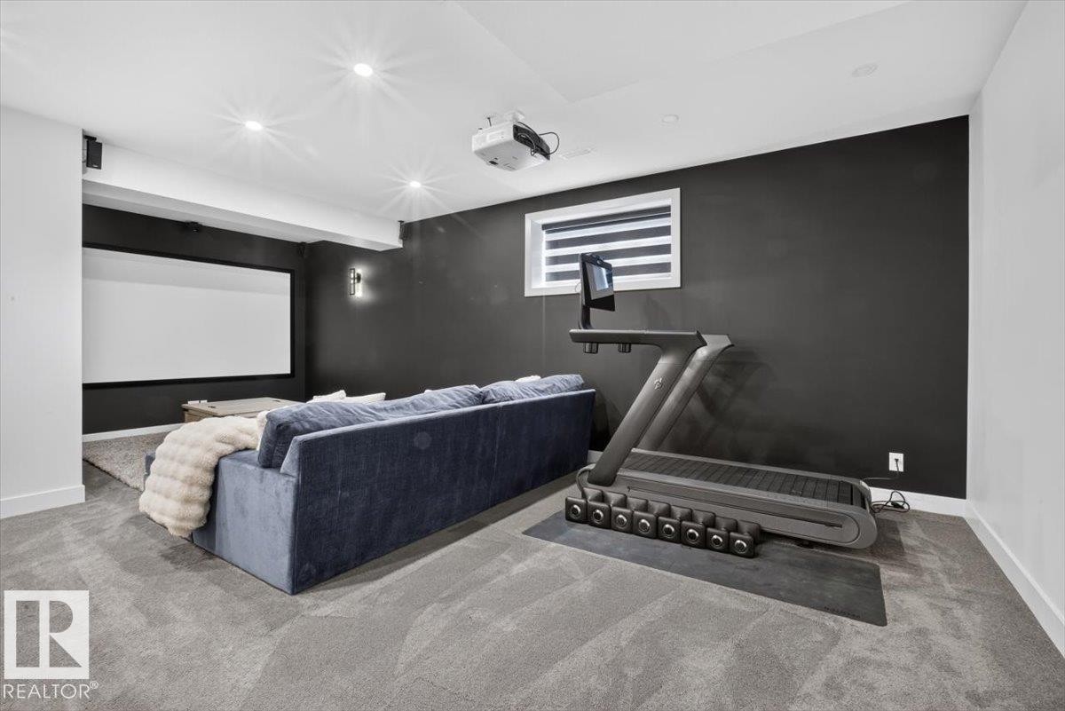 Projector screen, wall-mounted projector, wall sconce, recessed lighting, and grey carpeting - 94 Harvest Crescent, Ardrossan, AB - Indoor