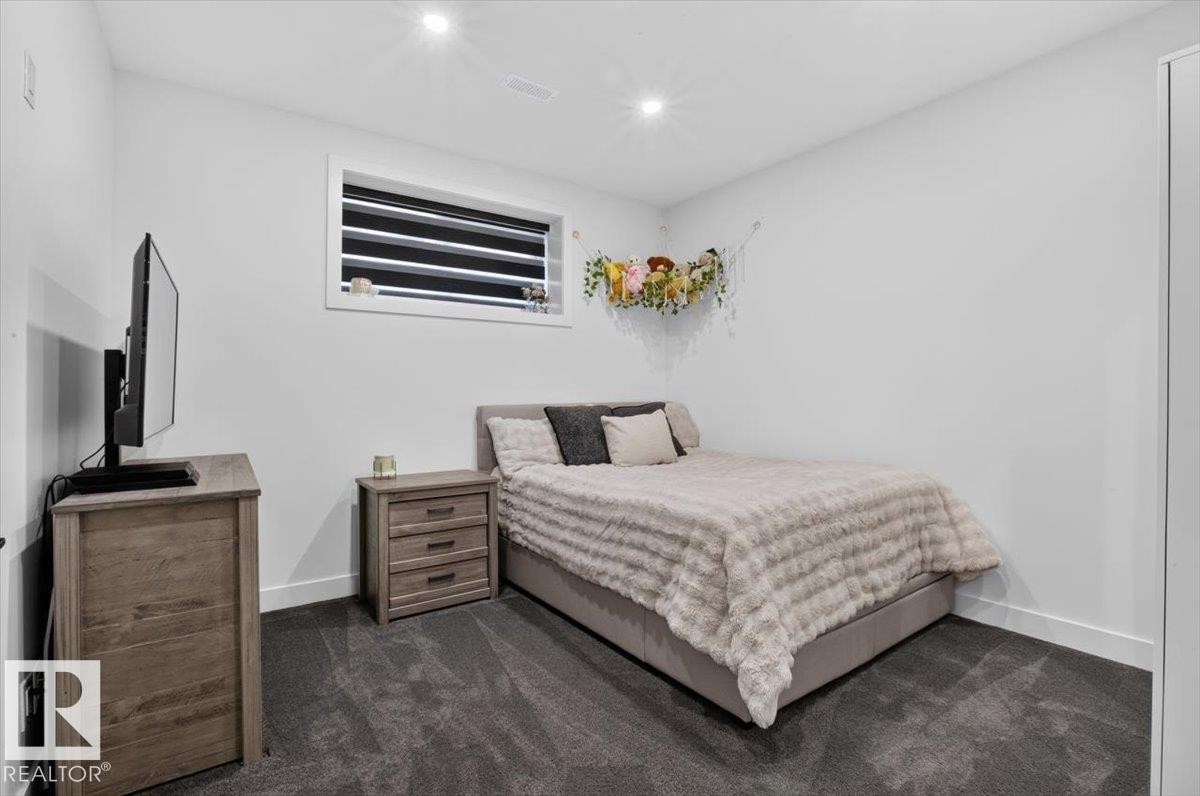 Recessed ceiling lighting, window with horizontal blinds, neutral wall tones, dark carpeting, and white baseboards - 94 Harvest Crescent, Ardrossan, AB - Indoor Photo Showing Bedroom