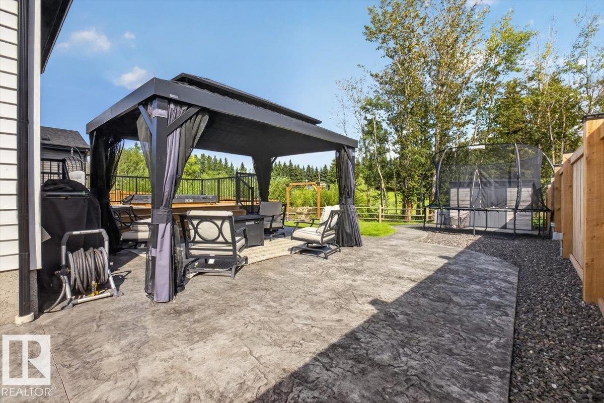 Stamped concrete patio with a covered gazebo, a raised wood deck, gravel landscaping, and a wood fence - 94 Harvest Crescent, Ardrossan, AB - Outdoor With Deck Patio Veranda