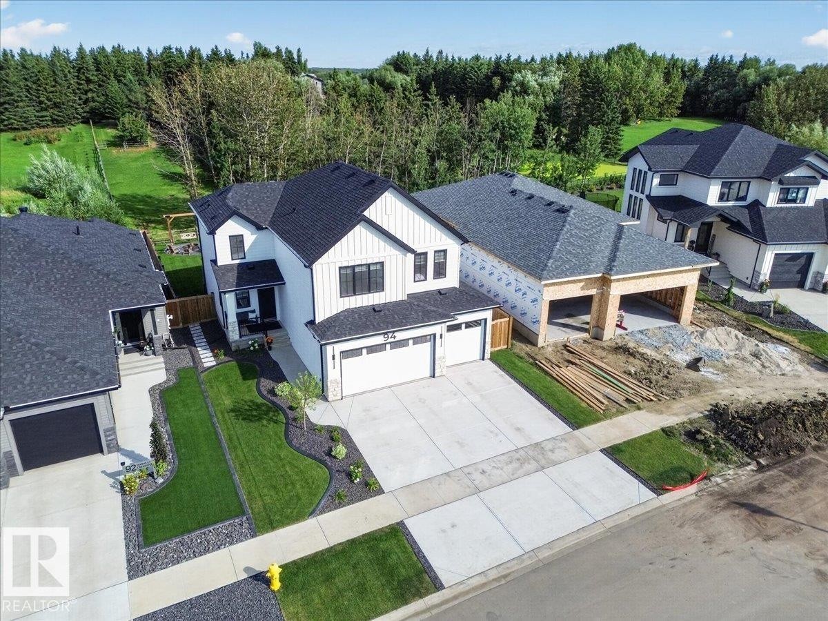 Modern exterior with white vertical siding and black trim accents - 94 Harvest Crescent, Ardrossan, AB - Outdoor With Deck Patio Veranda With Facade