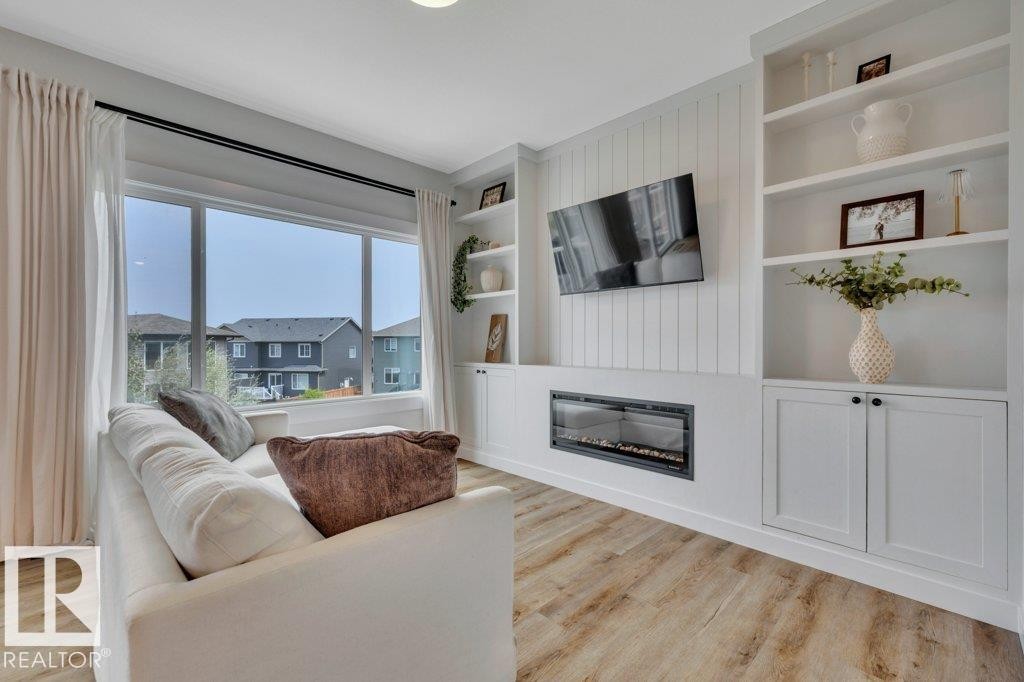 With large windows, custom finish cabinetry and shelves - 5329 Lark Landing Nw, Edmonton, AB - Indoor Photo Showing Living Room With Fireplace