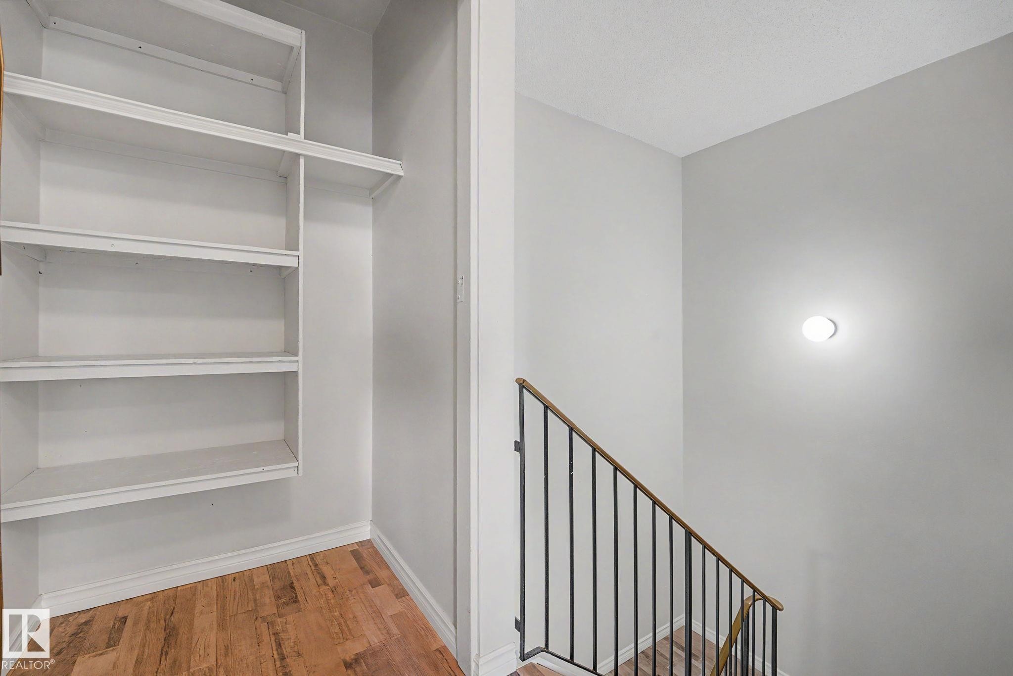 Built-in white shelving unit with wood-finish flooring - 1096 Knottwood Road Nw, Edmonton, AB - Indoor