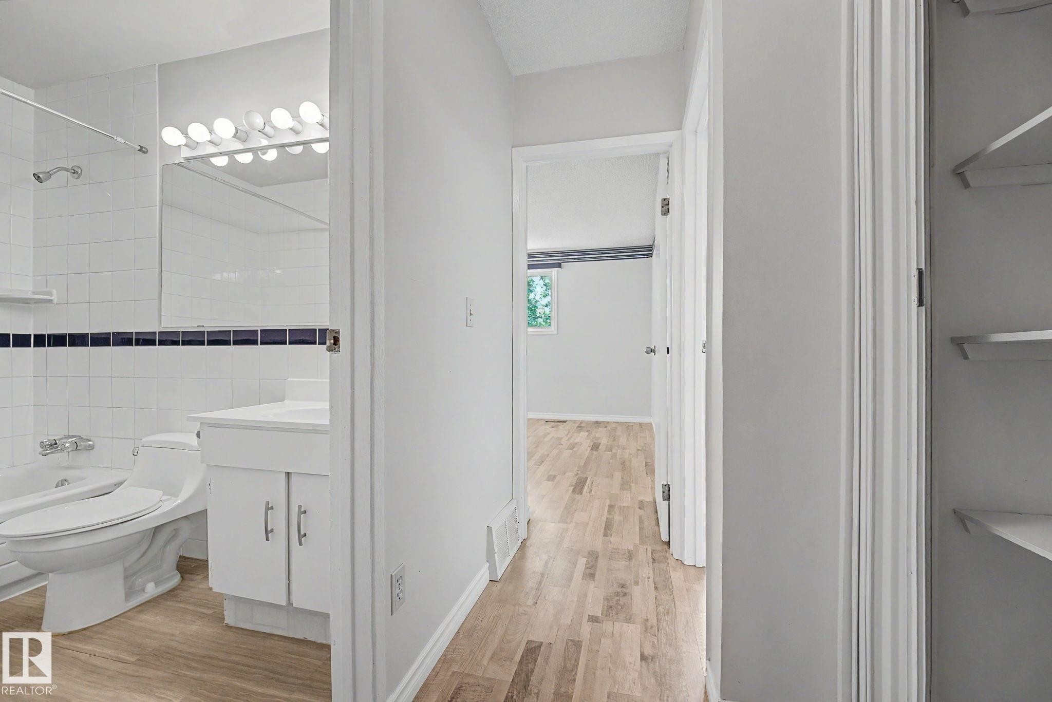 Hallway featuring light wood-finish flooring and a built-in linen closet with shelving - 1096 Knottwood Road Nw, Edmonton, AB - Indoor Photo Showing Bathroom