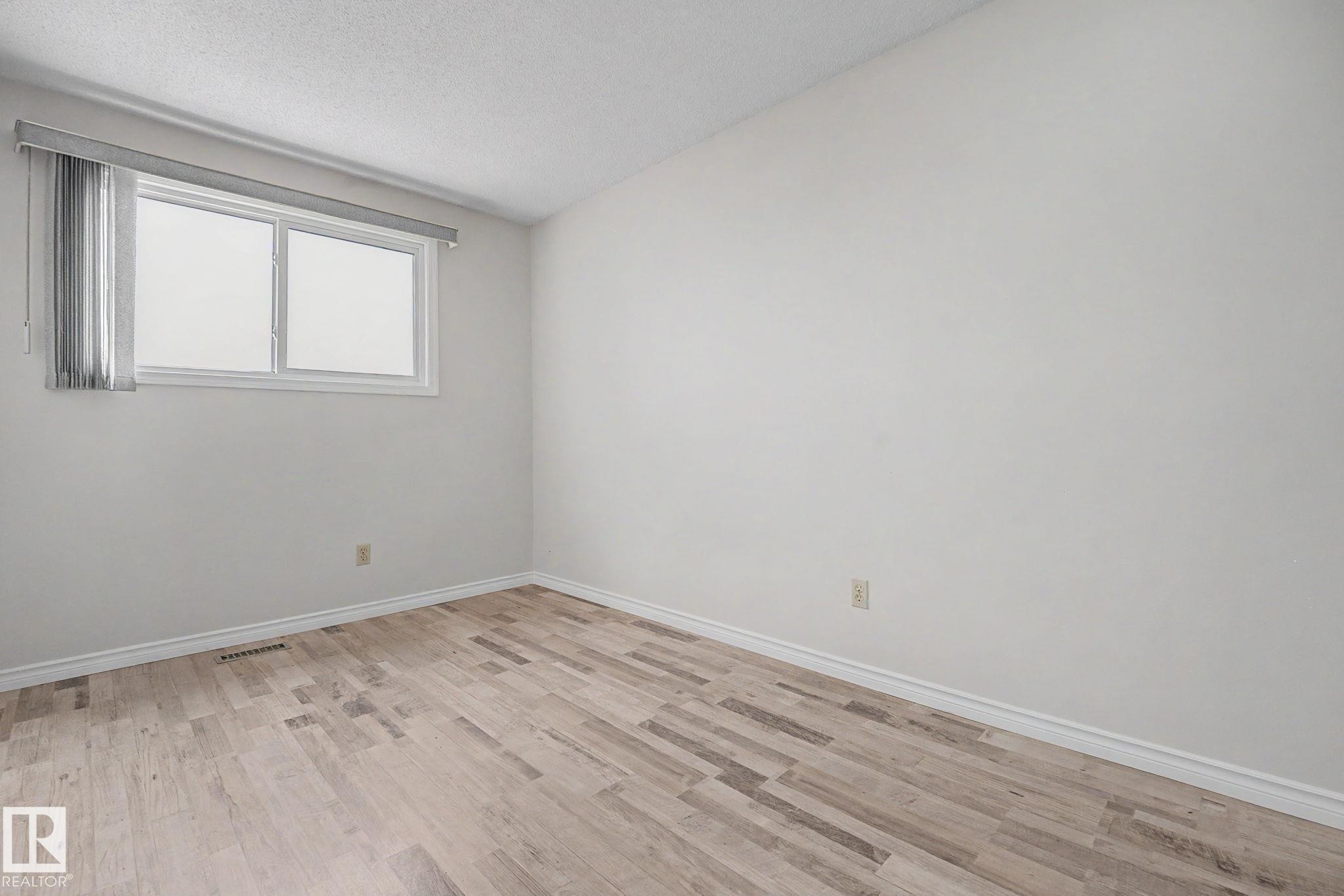 Room with light wood-finish flooring, white walls, and a white window frame with blinds - 1096 Knottwood Road Nw, Edmonton, AB - Indoor Photo Showing Other Room