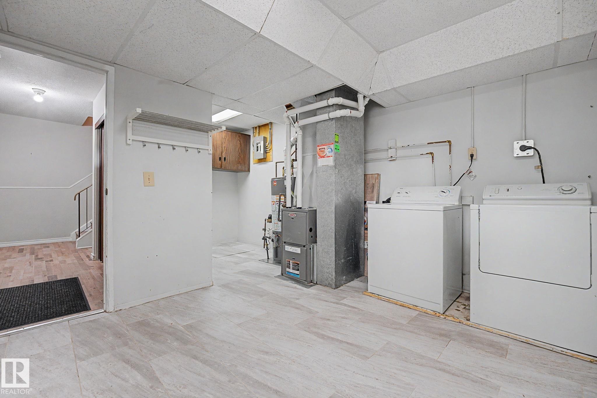 Utility area featuring light wood-finish flooring, a washer and dryer, and exposed ductwork - 1096 Knottwood Road Nw, Edmonton, AB - Indoor Photo Showing Laundry Room