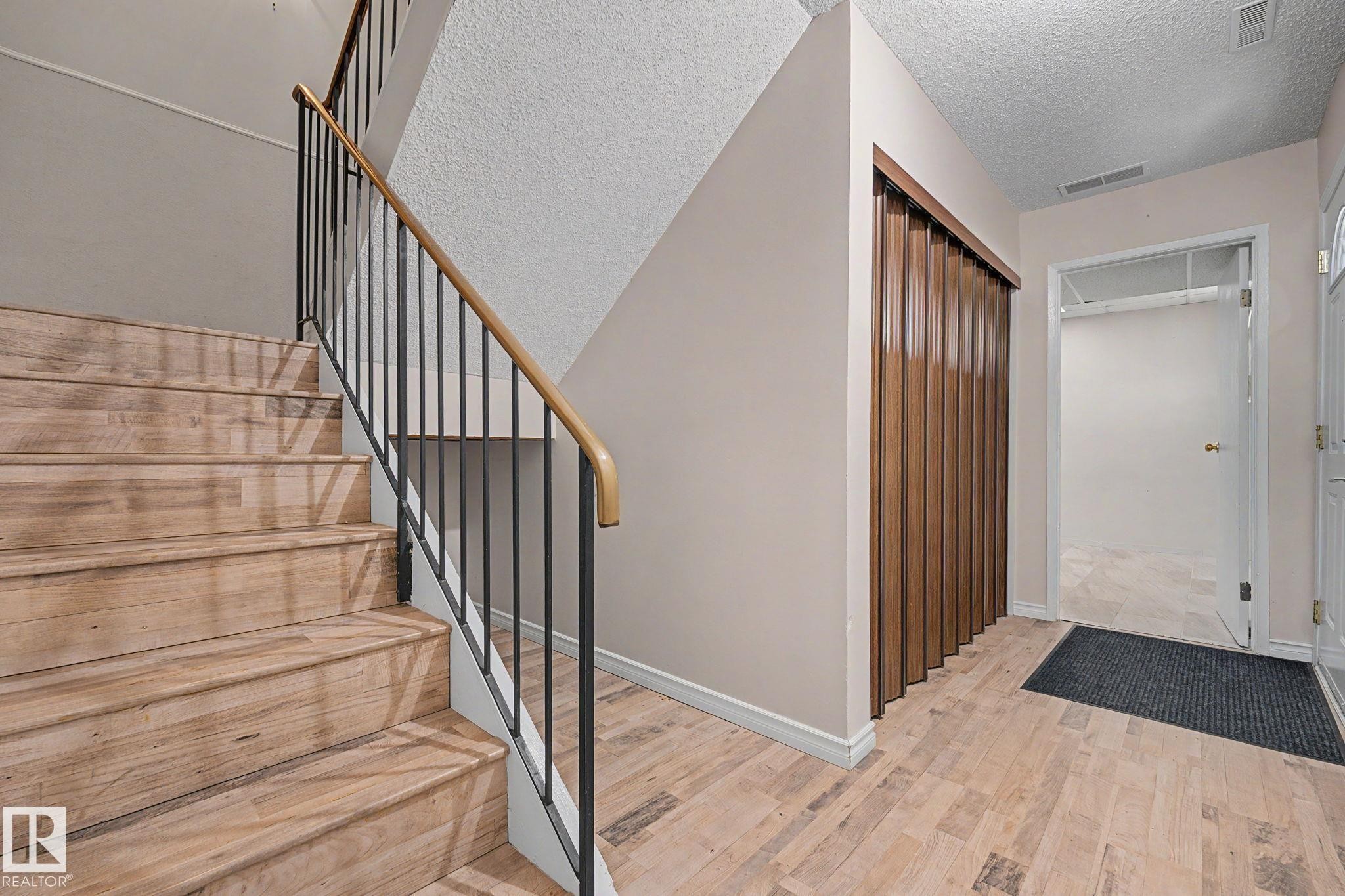 Wood-finish staircase with black metal balusters and a light wood handrail - 1096 Knottwood Road Nw, Edmonton, AB - Indoor Photo Showing Other Room