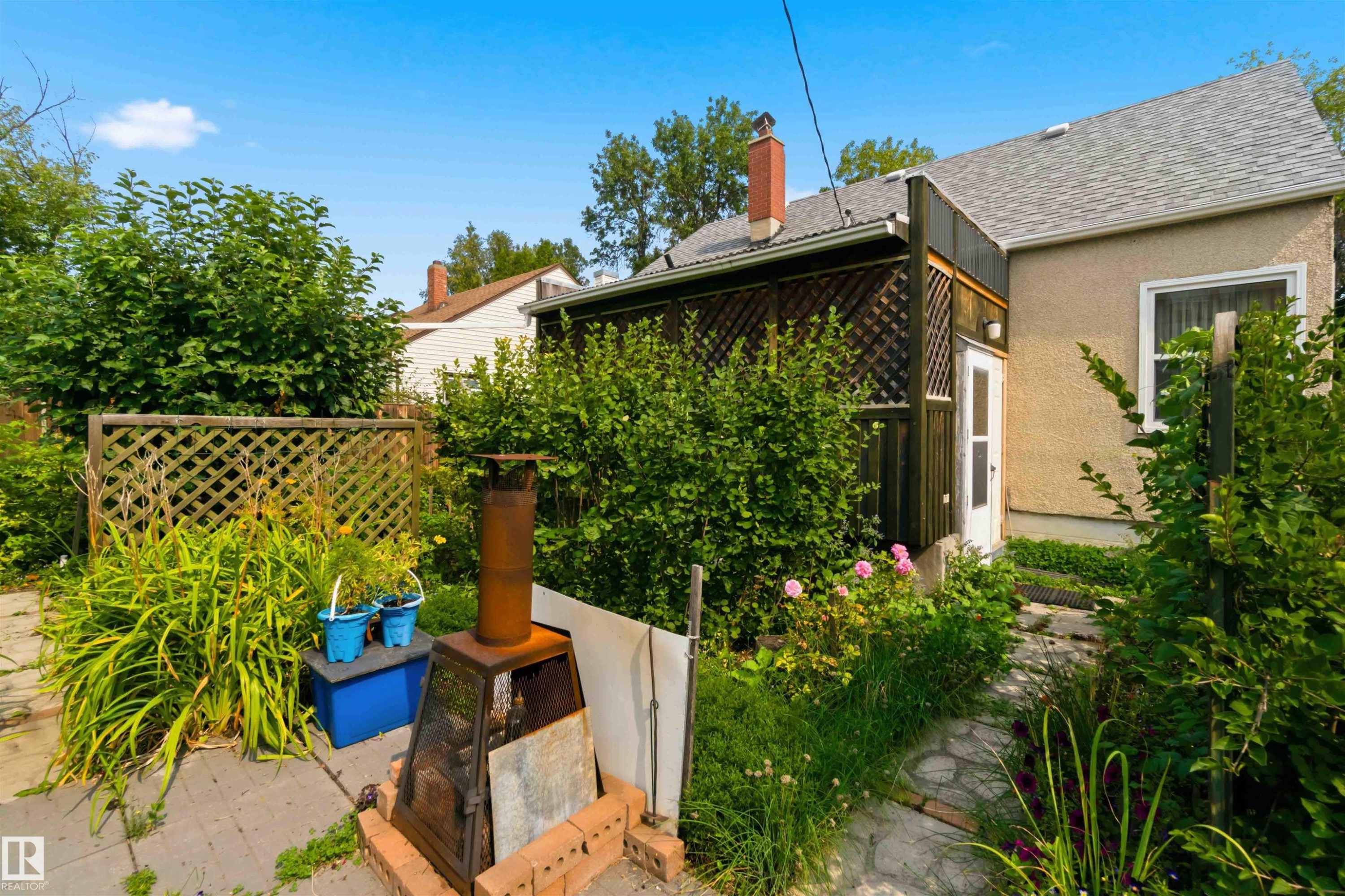 Backyard featuring a stone paver path, mature landscaping, and a lattice privacy screen - 11710 94 Street Nw, Edmonton, AB - Outdoor