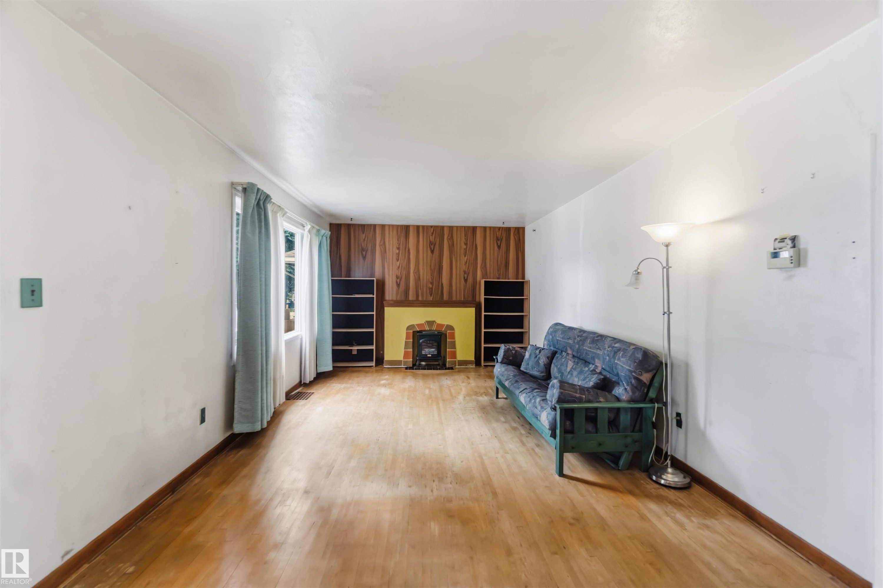 Spacious recreation room featuring hardwood flooring, white walls, and abundant natural light from multiple windows - 11710 94 Street Nw, Edmonton, AB - Indoor With Fireplace