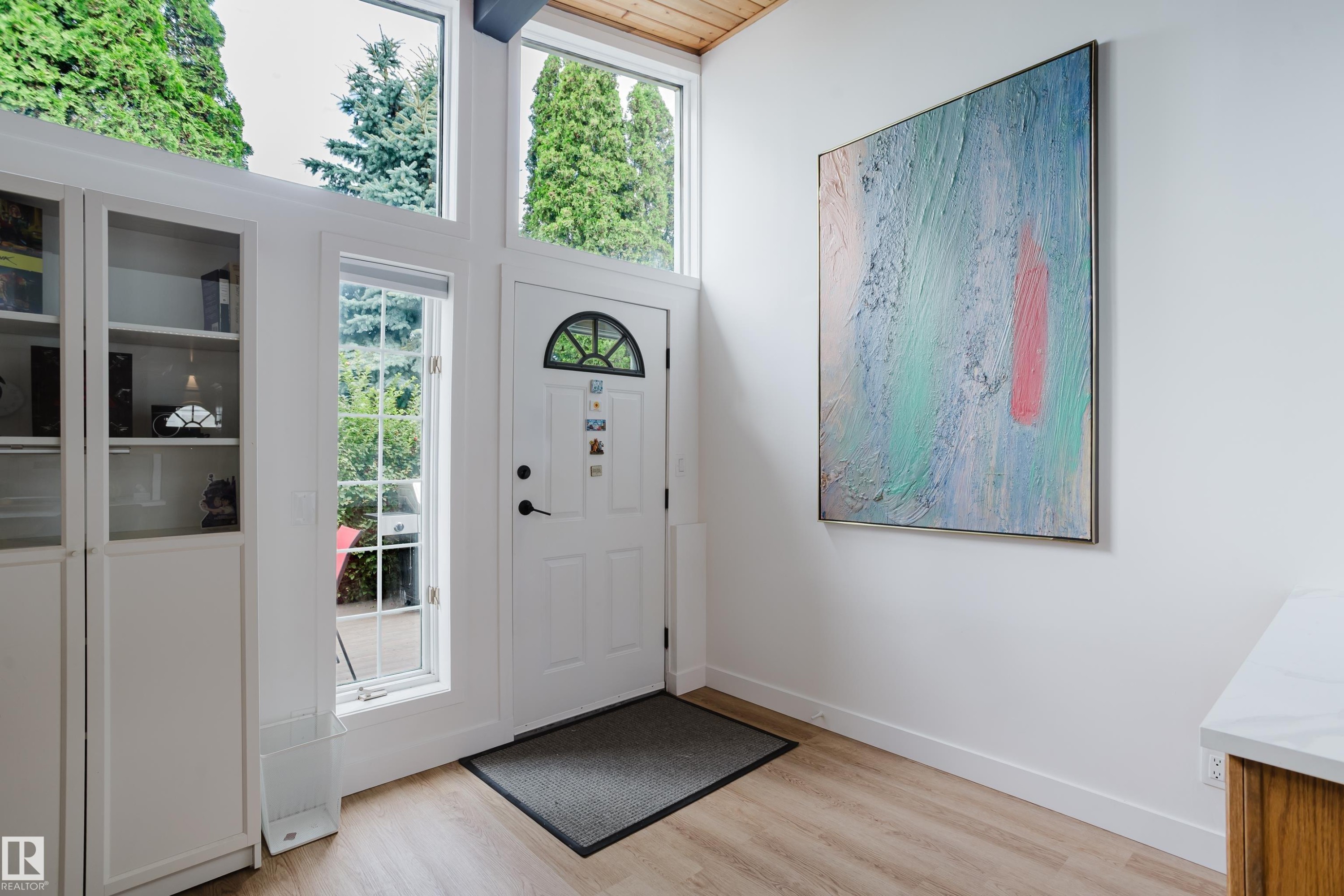 White entryway door with an arched transom window, flanked by tall windows and built-in white cabinetry with glass inserts - 9059 52 Street Nw, Edmonton, AB - Indoor Photo Showing Other Room
