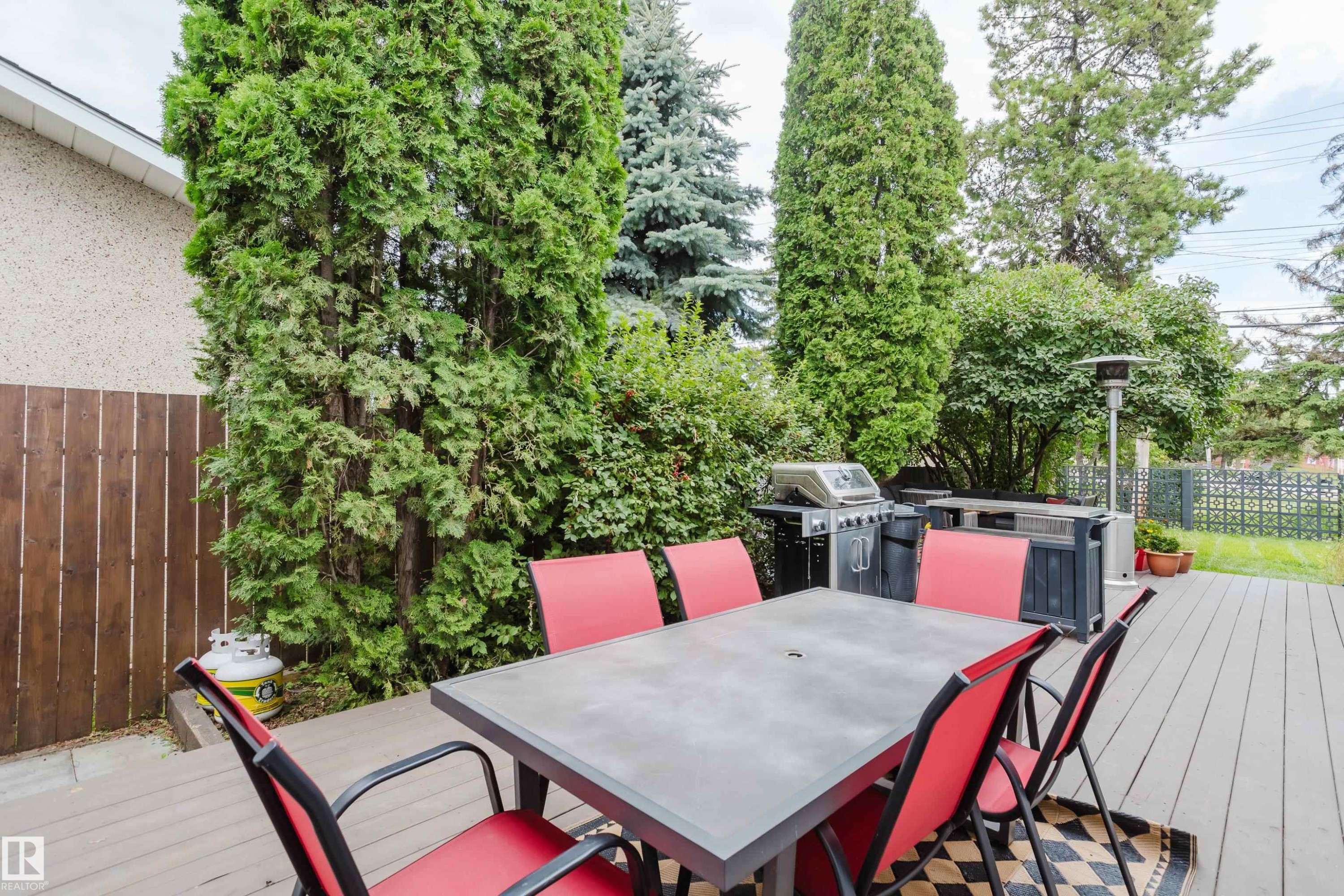 Deck featuring composite decking, privacy fencing, and mature landscaping - 9059 52 Street Nw, Edmonton, AB - Outdoor With Deck Patio Veranda