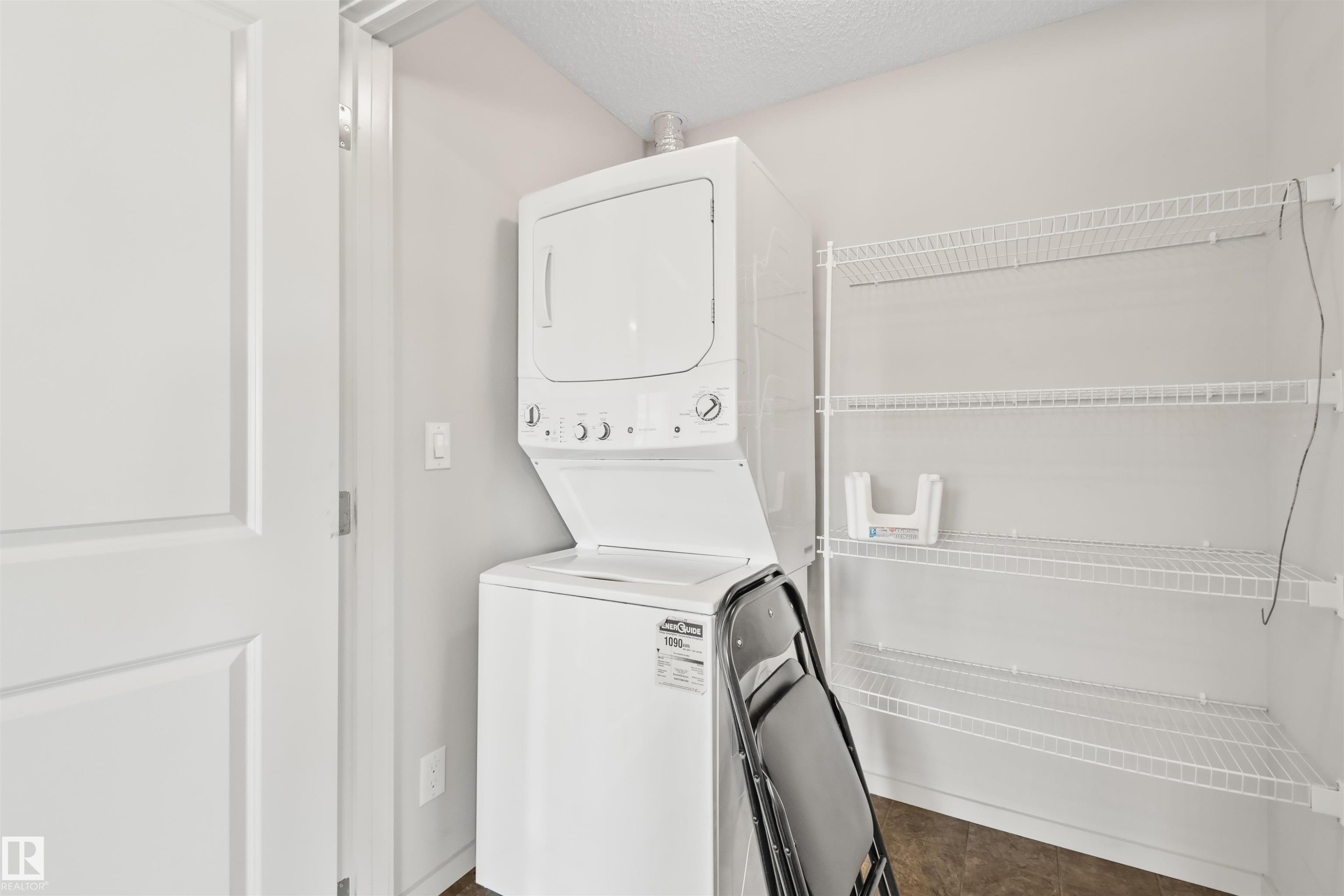 Integrated stackable washer and dryer, wire shelving storage system, and panel door - #318 5521 7 Av Sw Sw, Edmonton, AB - Indoor Photo Showing Laundry Room