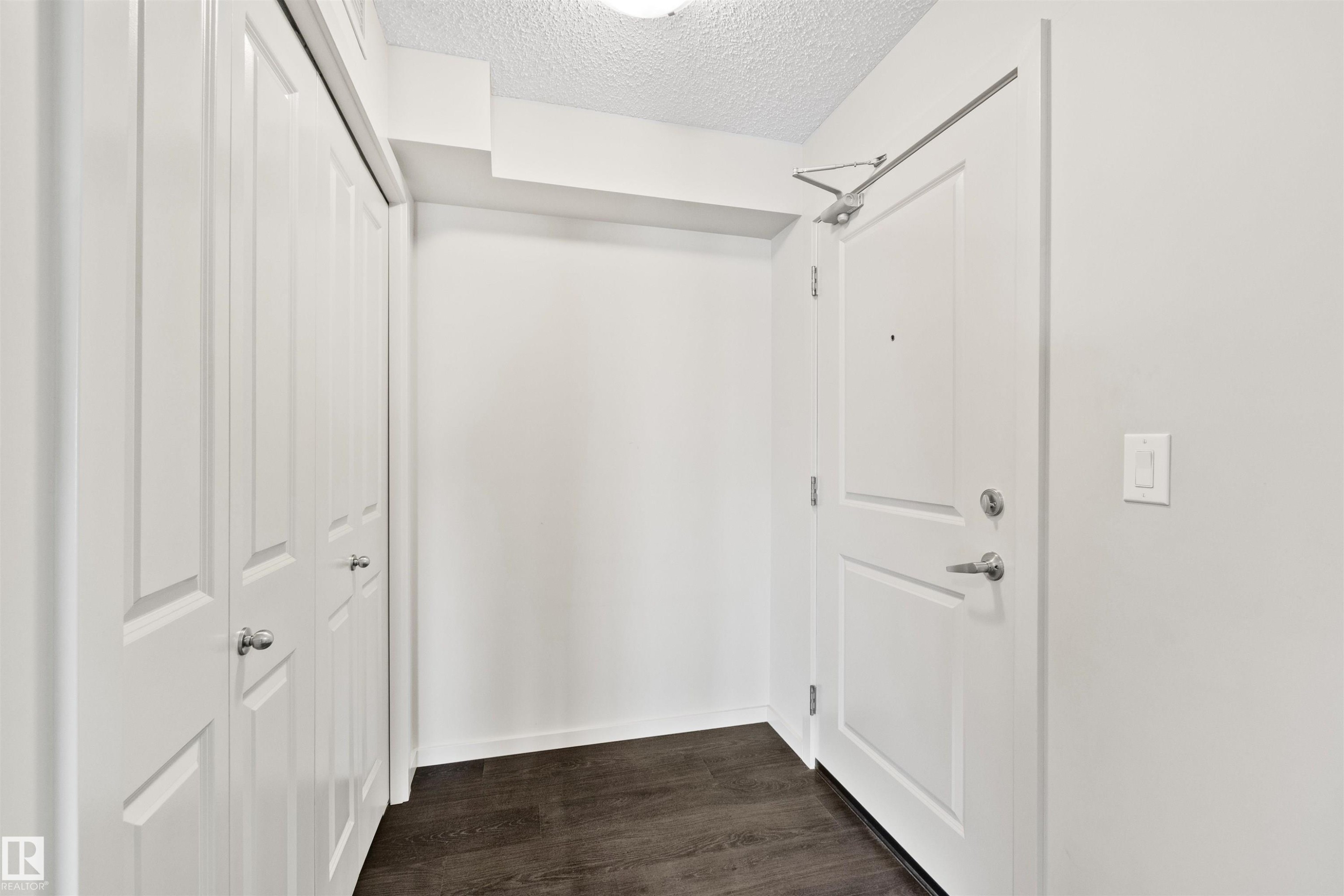 Wood-finish flooring, white walls, white paneled doors, and brushed nickel hardware - #318 5521 7 Av Sw Sw, Edmonton, AB - Indoor Photo Showing Other Room