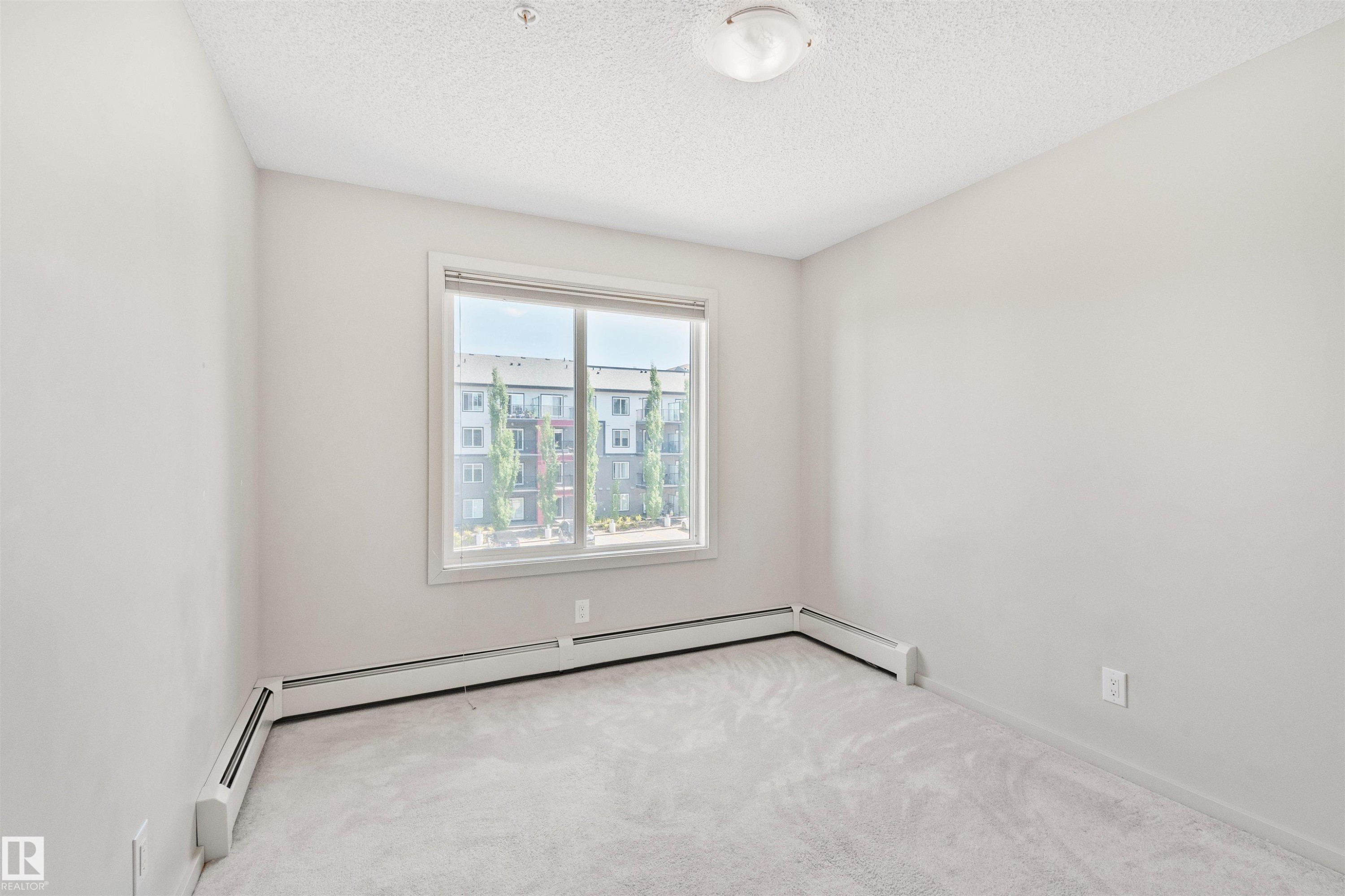 Light-colored walls, carpet flooring, a window with white trim, and a ceiling-mounted light fixture - #318 5521 7 Av Sw Sw, Edmonton, AB - Indoor Photo Showing Other Room