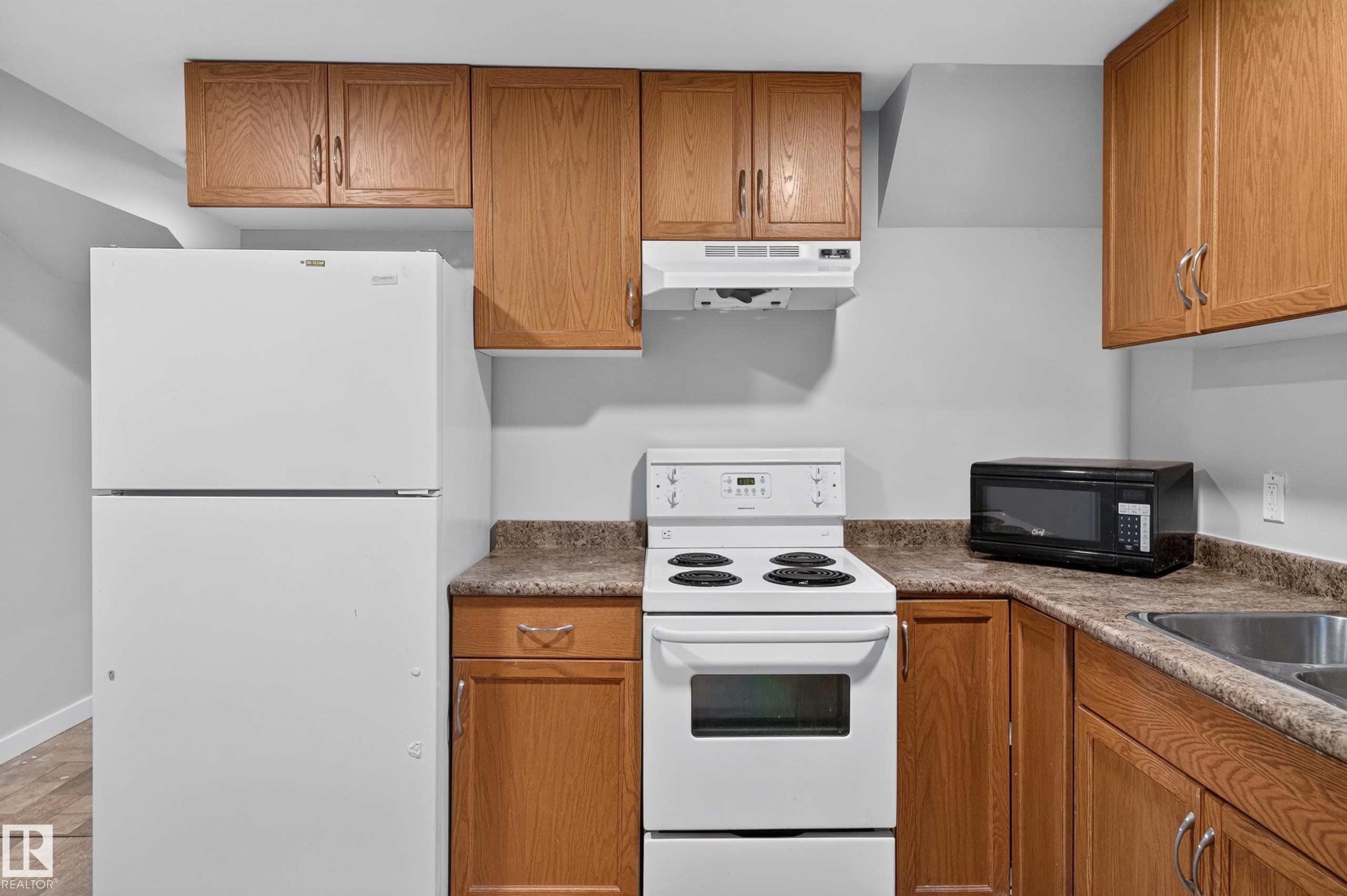 Kitchen featuring wood cabinetry, white refrigerator, white electric range, and a dual basin sink - 13214 123 Street Nw, Edmonton, AB