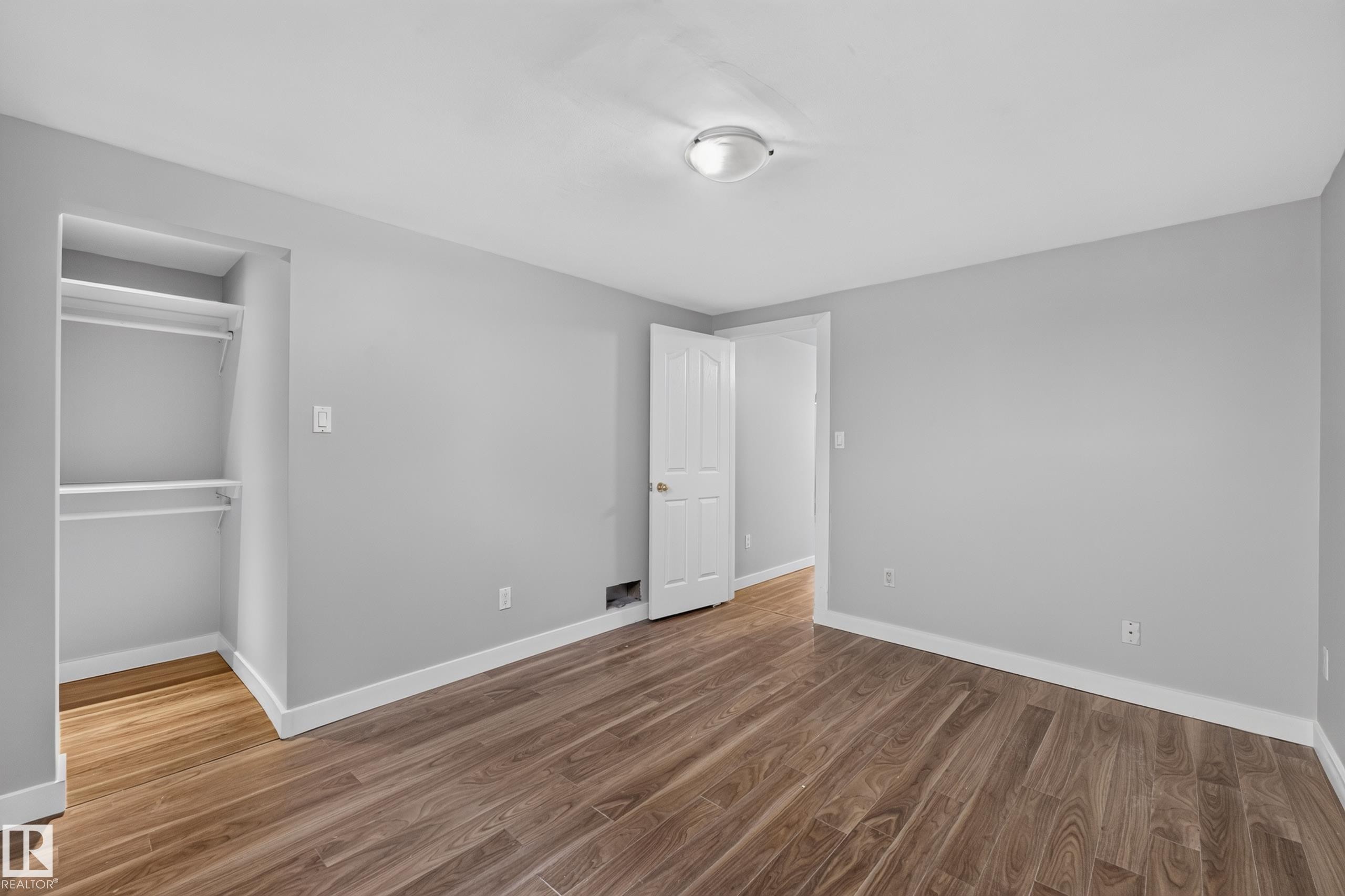 Wood-finish flooring, light gray wall tones, ceiling-mounted lighting, white trim, and built-in closet shelving - 13214 123 Street Nw, Edmonton, AB