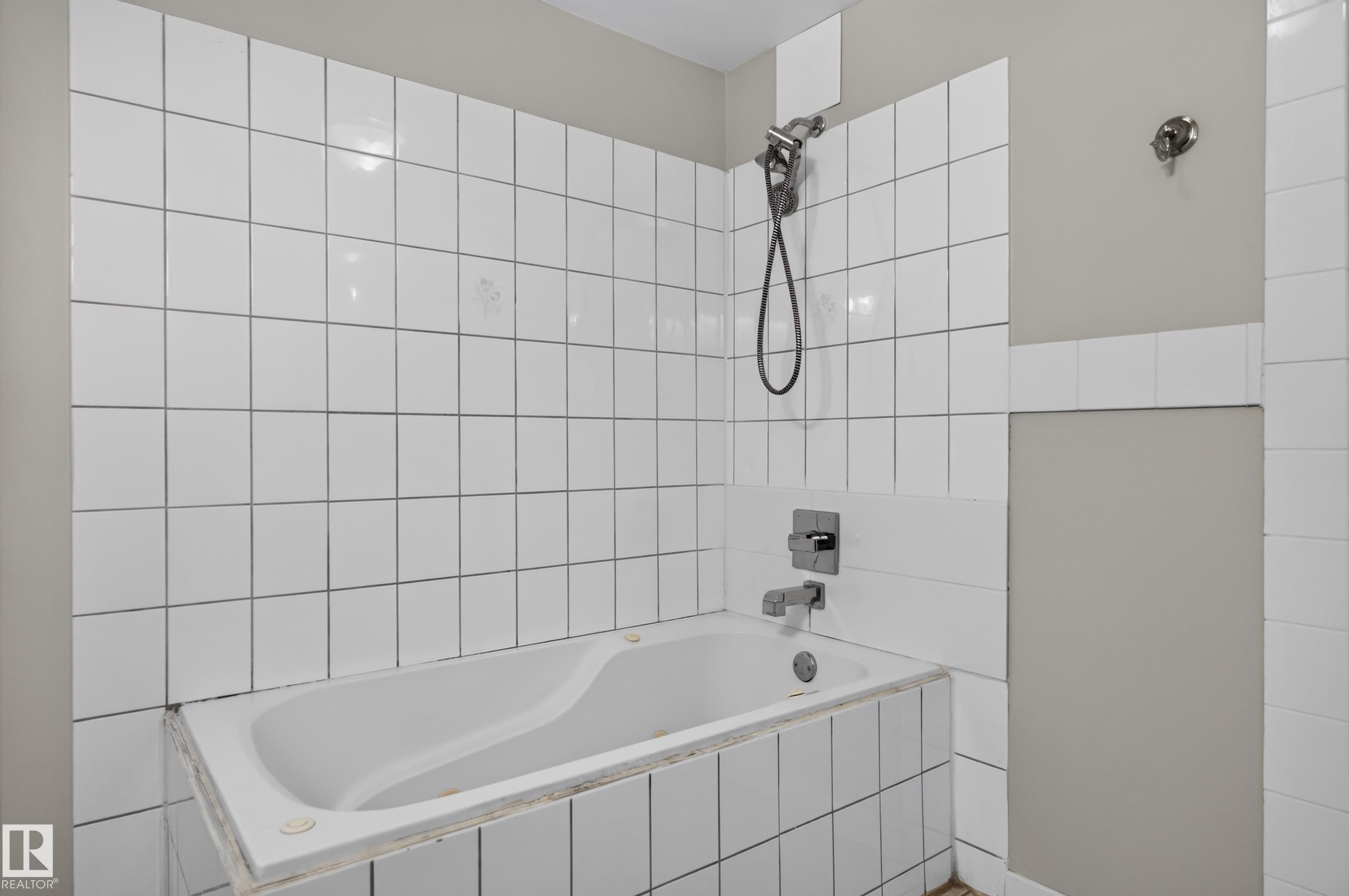 Bathtub with white tile surround and wall-mounted shower fixture - 13214 123 Street Nw, Edmonton, AB