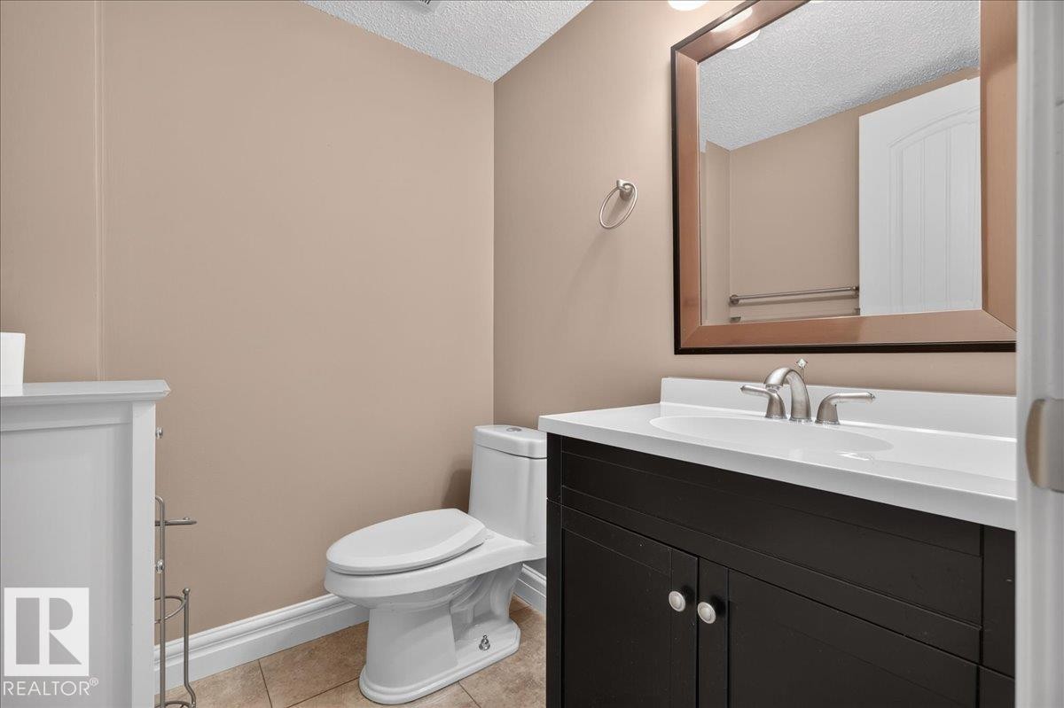 Powder room featuring a dark wood-finish vanity with a white countertop, chrome faucet, and a large framed mirror - #47 3812 20 Av Nw, Edmonton, AB