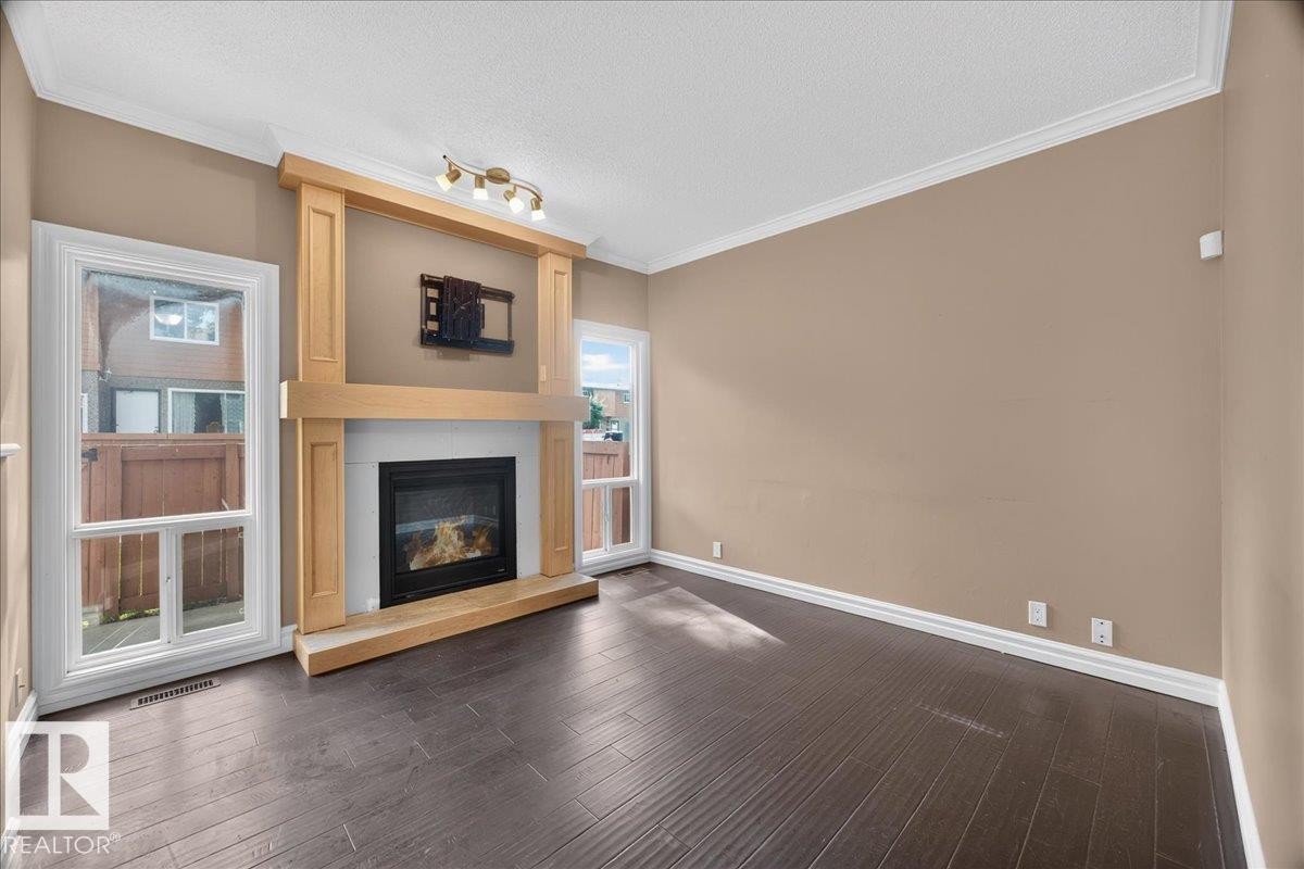 Hardwood-style flooring, gas fireplace with wood surround, crown molding, and recessed lighting - #47 3812 20 Av Nw, Edmonton, AB