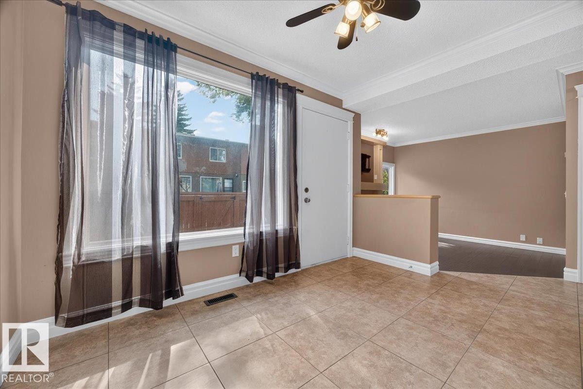 Tiled flooring, large window, ceiling fan with integrated lighting, and crown molding - #47 3812 20 Av Nw, Edmonton, AB