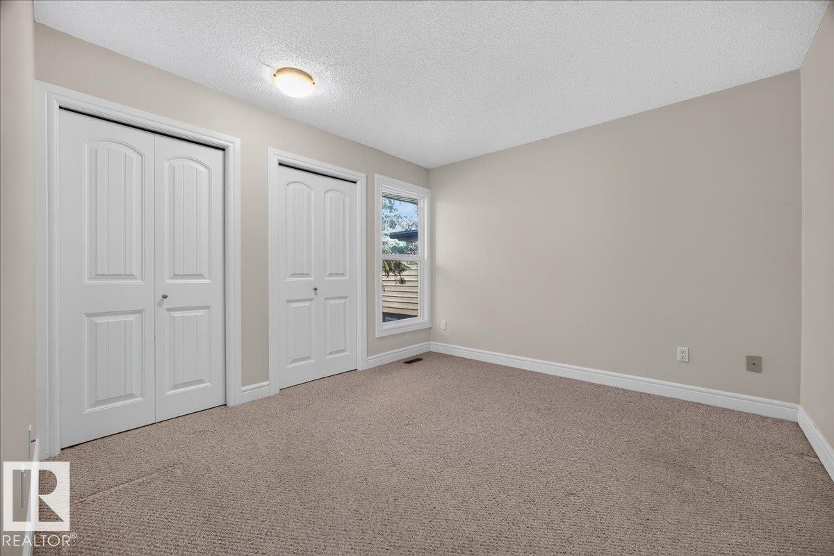 Neutral-toned carpeting, light wall paint, dual white bi-fold closet doors, and natural light from a rectangular window - #47 3812 20 Av Nw, Edmonton, AB