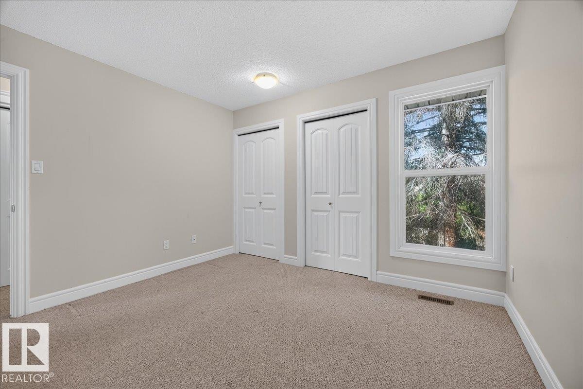 Neutral tone wall paint, carpet flooring, two bi-fold closet doors, and a double-hung window with white trim - #47 3812 20 Av Nw, Edmonton, AB