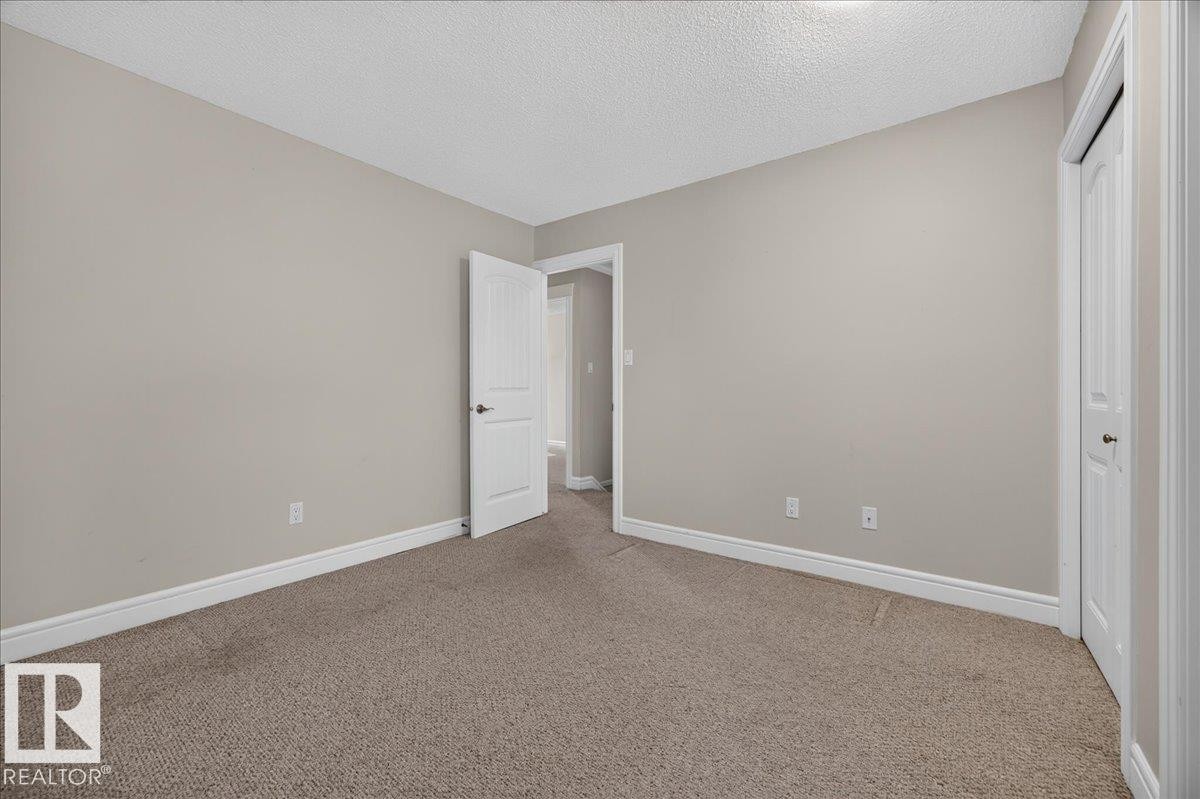 Neutral-toned walls, textured carpet flooring, white trim, and a paneled door - #47 3812 20 Av Nw, Edmonton, AB
