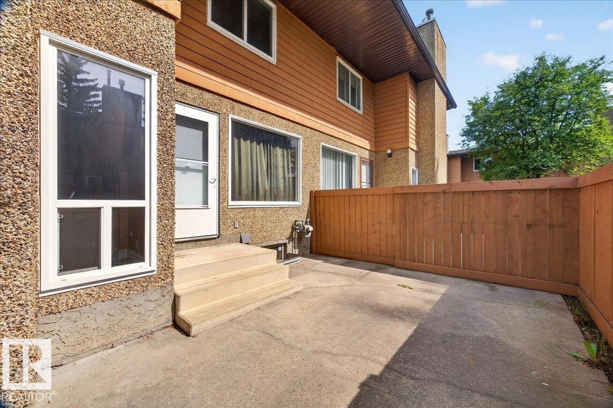 Private concrete patio featuring a wood privacy fence and exterior entry - #47 3812 20 Av Nw, Edmonton, AB