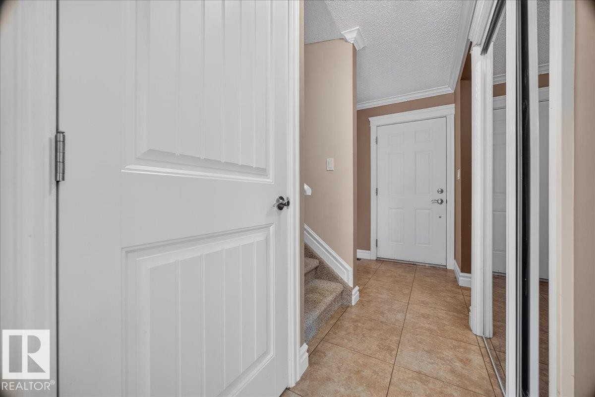 Foyer featuring tiled flooring, white paneled doors, and a mirrored closet - #47 3812 20 Av Nw, Edmonton, AB