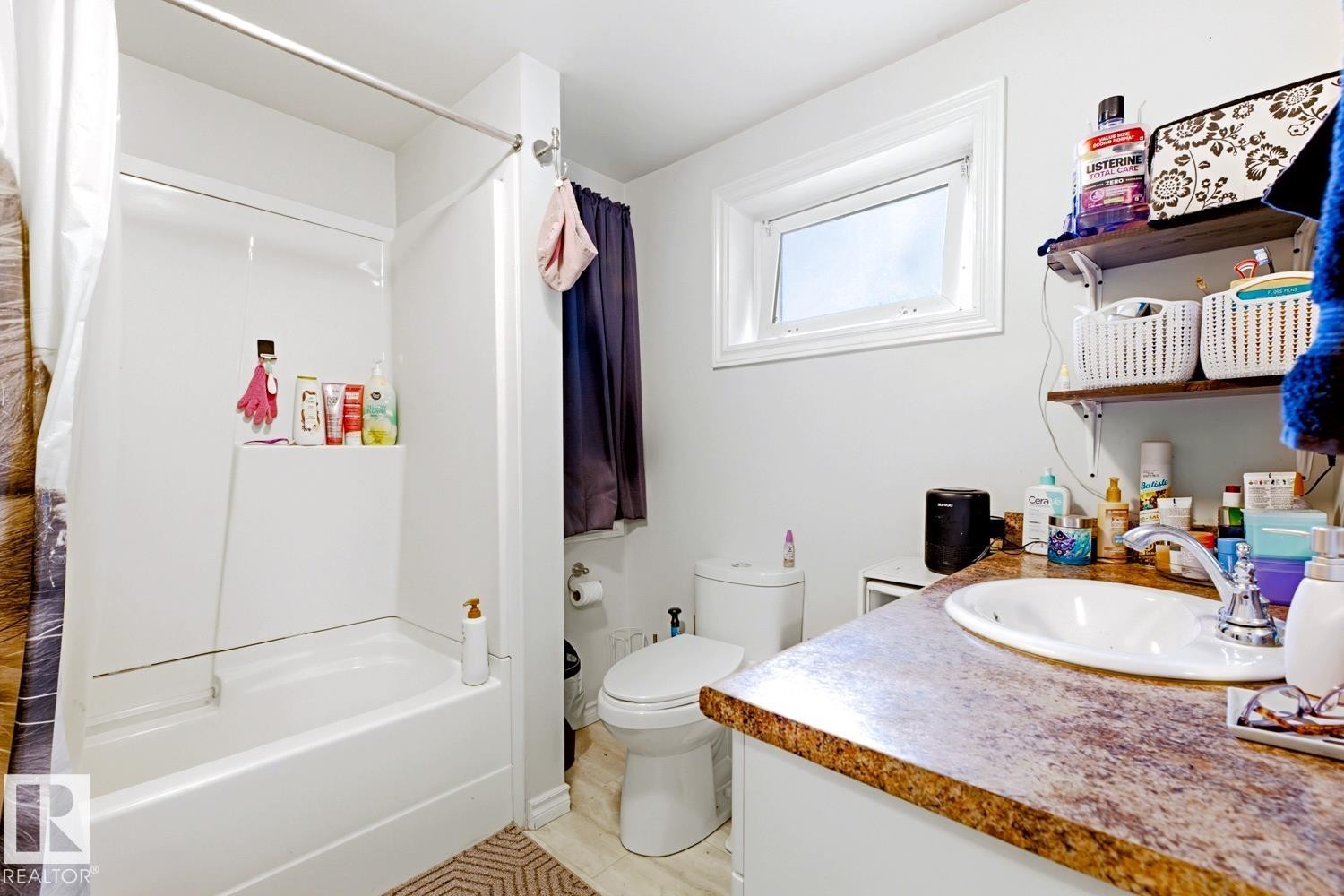 Bathroom featuring a wood-finish vanity with a vessel sink, stone countertop, and ample storage - 9740 63 Avenue Nw, Edmonton, AB