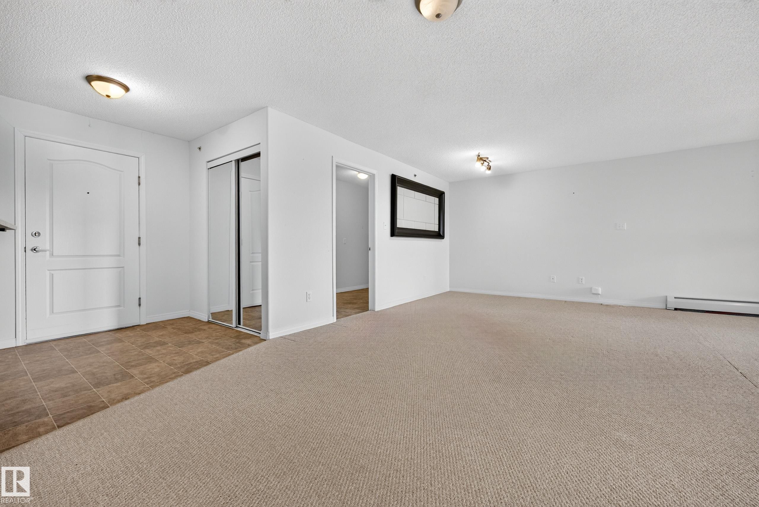 Entry with white paneled door, light-toned tile flooring, and mirrored closet doors - #6430 7331 South Terwillegar Dr Nw, Edmonton, AB