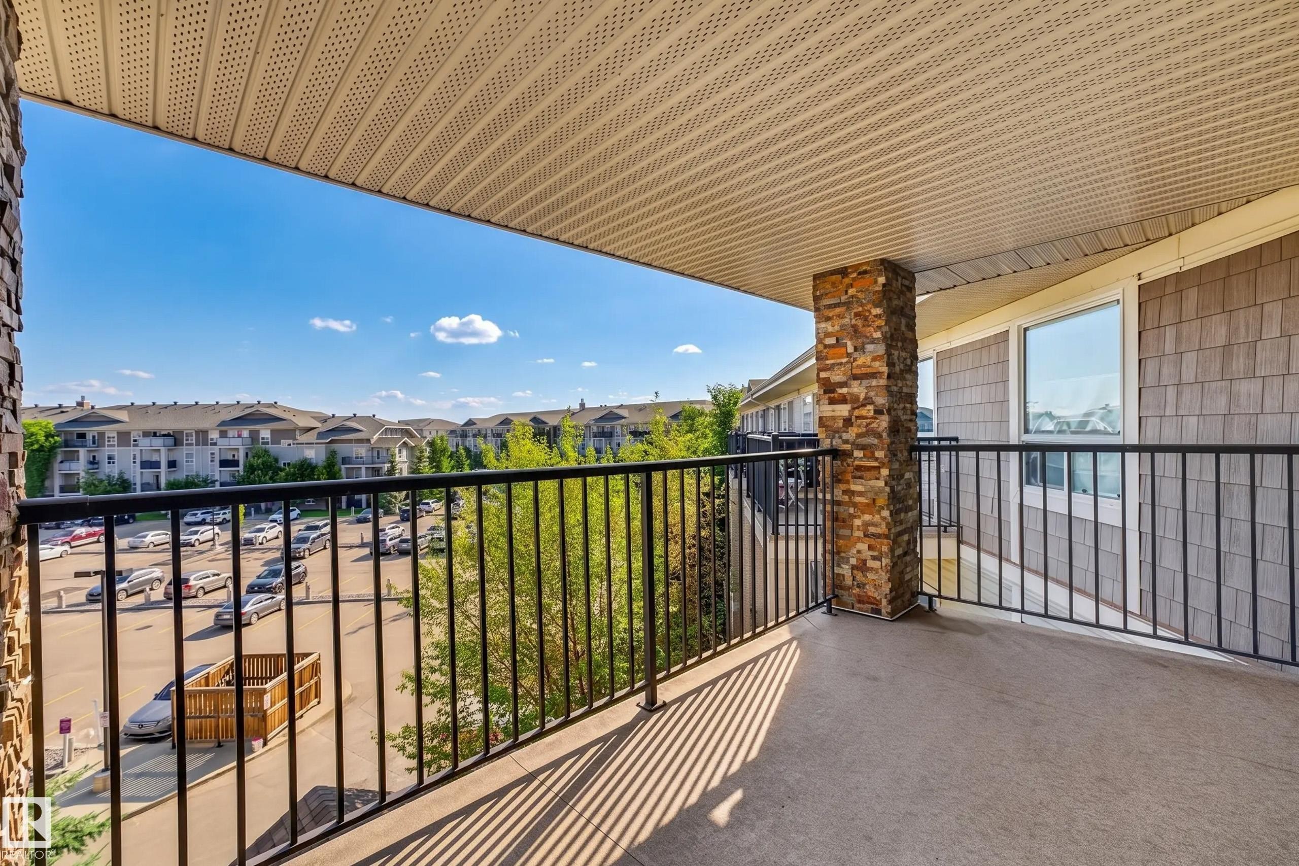 Spacious balcony with concrete flooring, stone-clad pillar, and black metal railing - #6430 7331 South Terwillegar Dr Nw, Edmonton, AB