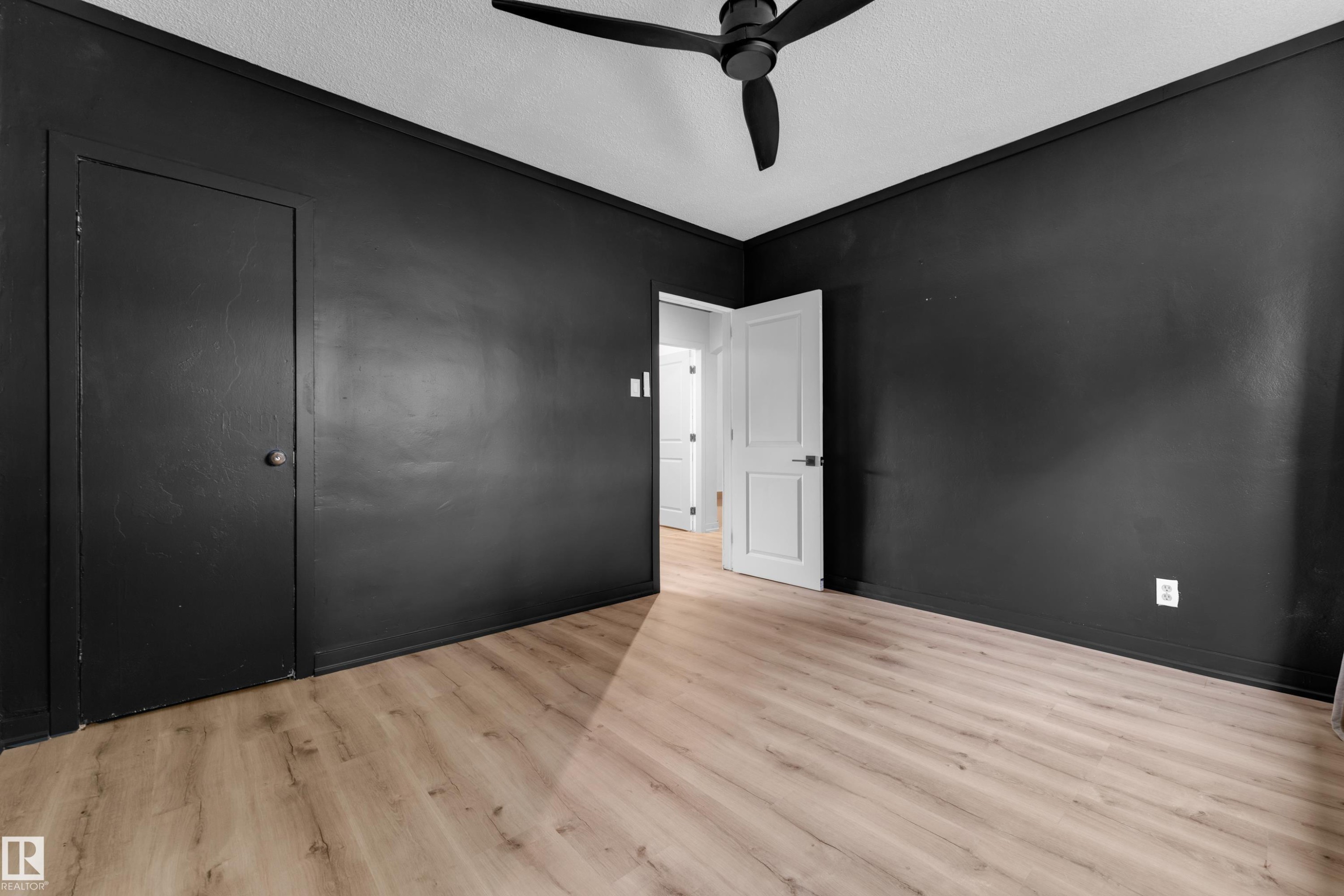 Wood-finish flooring, dark wall paint, ceiling fan, and white interior door - 12116 81 Street Nw, Edmonton, AB