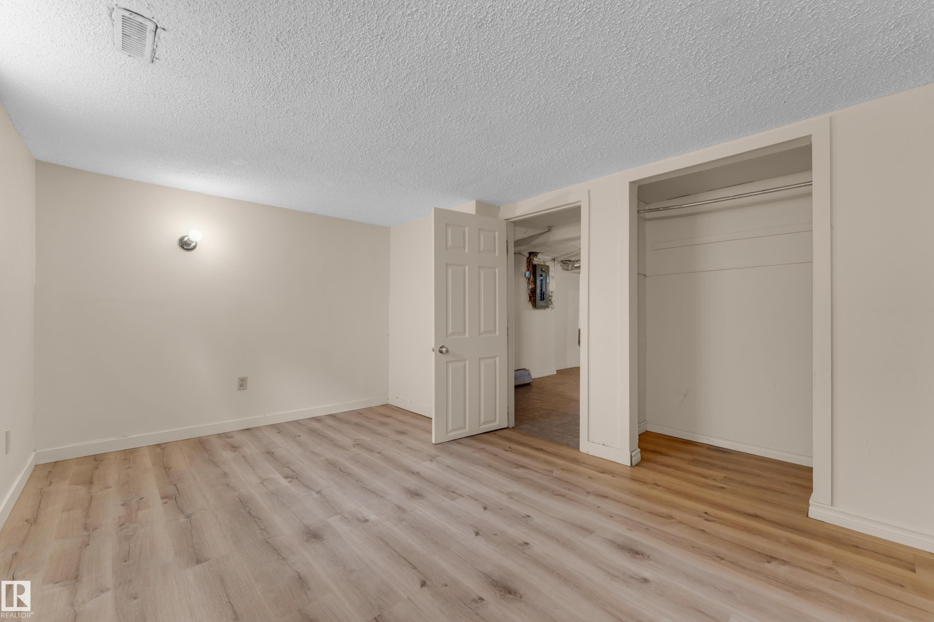 Wood-finish flooring, neutral wall paint, built-in closet with hanging rod, and ceiling-mounted light fixture - 12116 81 Street Nw, Edmonton, AB