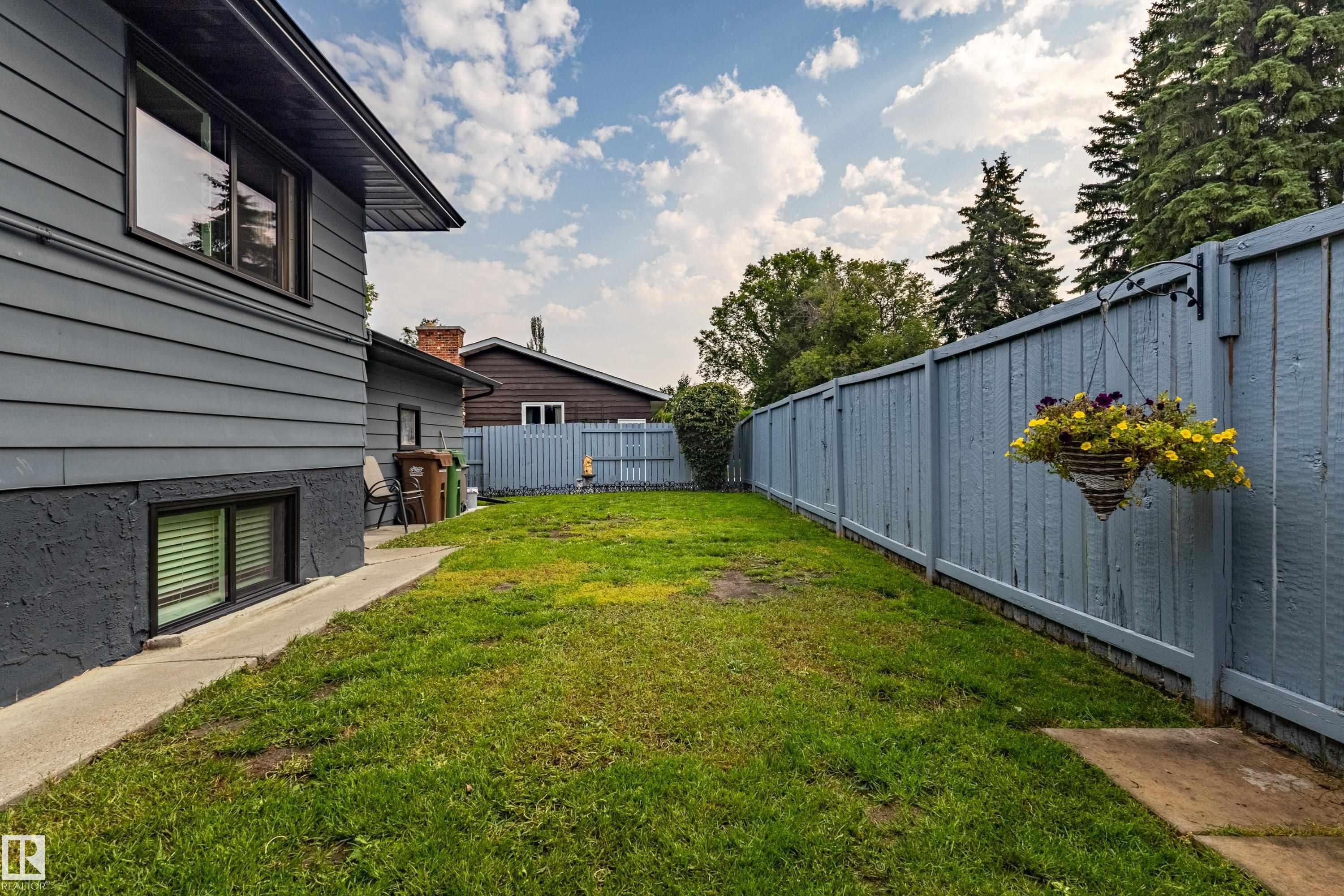 Expansive backyard featuring a manicured lawn, a concrete walkway, and a privacy fence - 14 Brunswick Crescent, St. Albert, AB