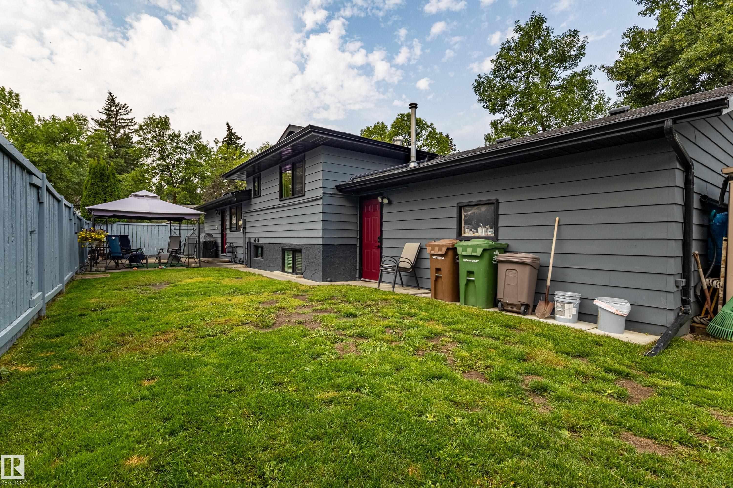 Expansive backyard with a manicured lawn, complete with a dedicated patio area, and a privacy fence - 14 Brunswick Crescent, St. Albert, AB