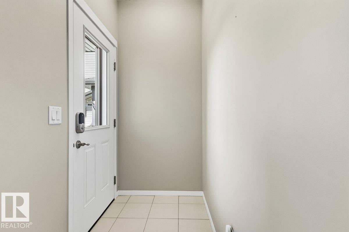 Entryway featuring a white door with an integrated window, smart lock, and neutral-toned wall paint - 1807 Westerra Loop, Stony Plain, AB