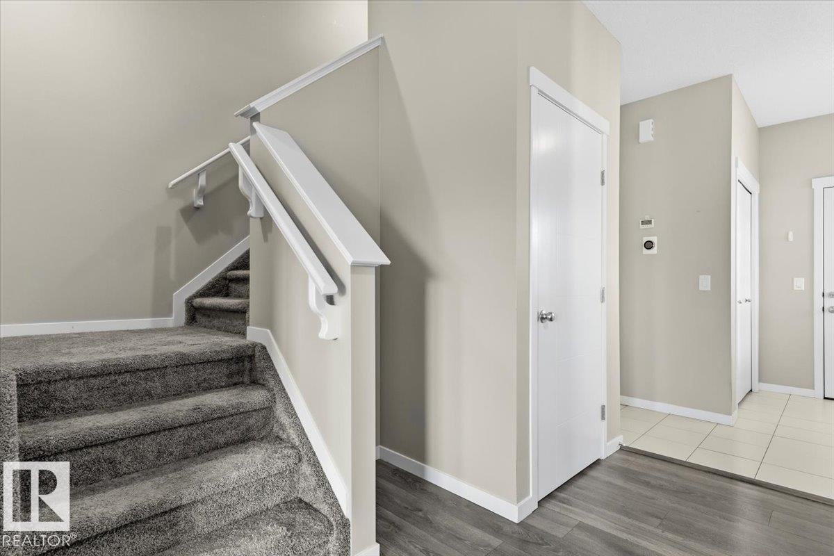 Carpeted staircase with white handrails, wood-finish flooring, and light-toned wall paint - 1807 Westerra Loop, Stony Plain, AB