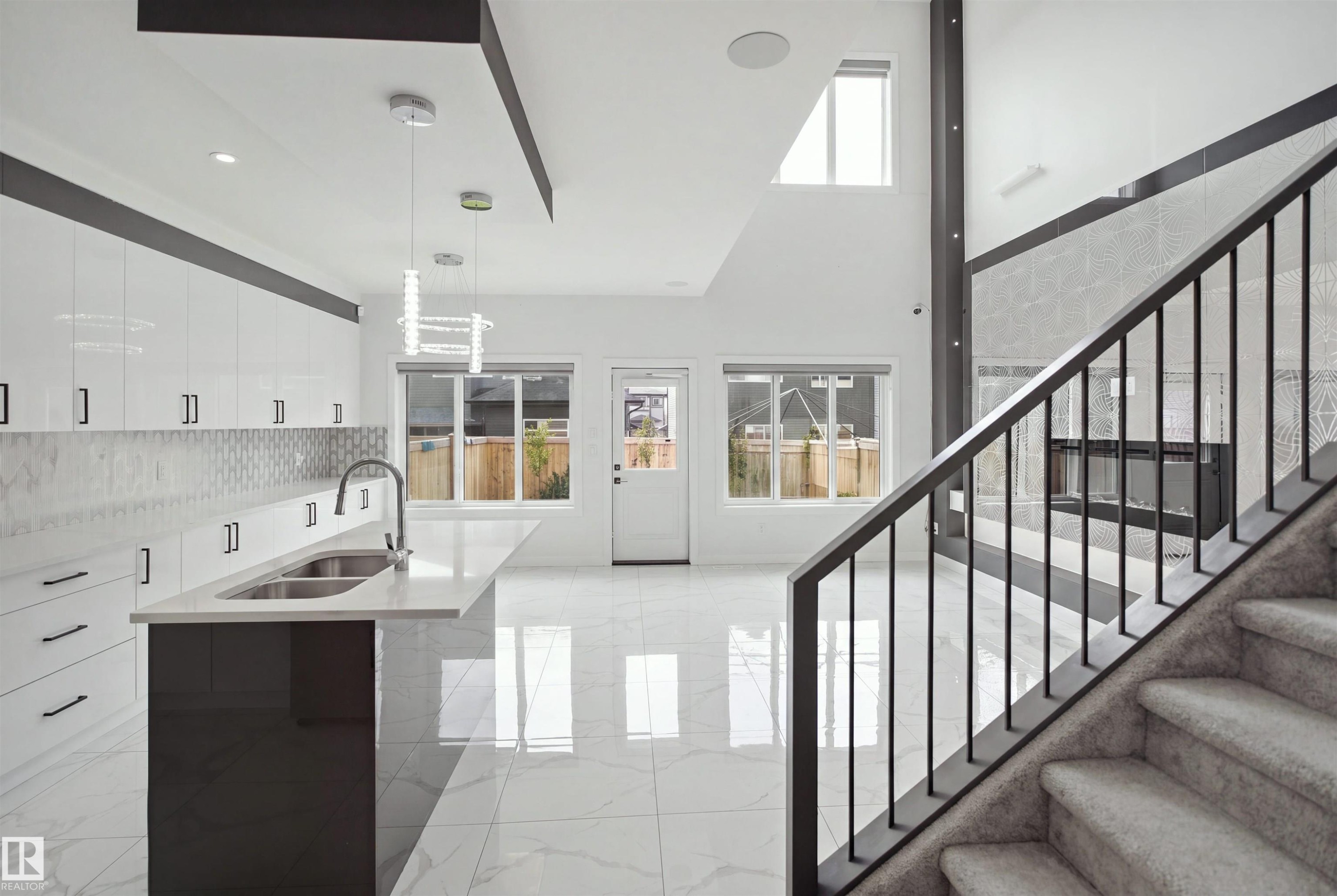 Contemporary kitchen with white cabinetry, a large island featuring an undermount double sink, and sleek tile flooring - 2027 13 Avenue Nw, Edmonton, AB