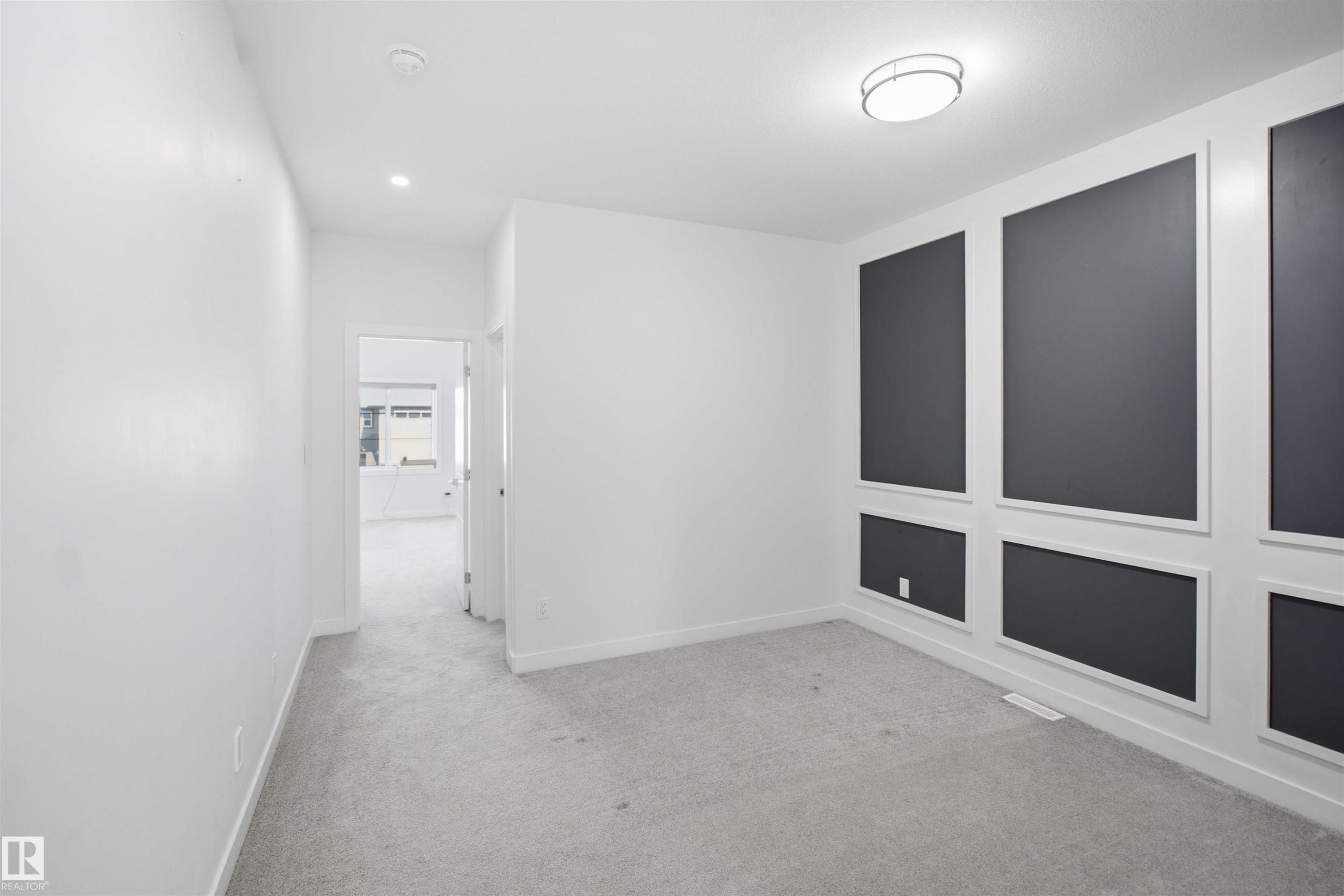 Accent wall with decorative molding, flush mount ceiling fixture, recessed lighting, white interior walls, and gray carpet - 2027 13 Avenue Nw, Edmonton, AB