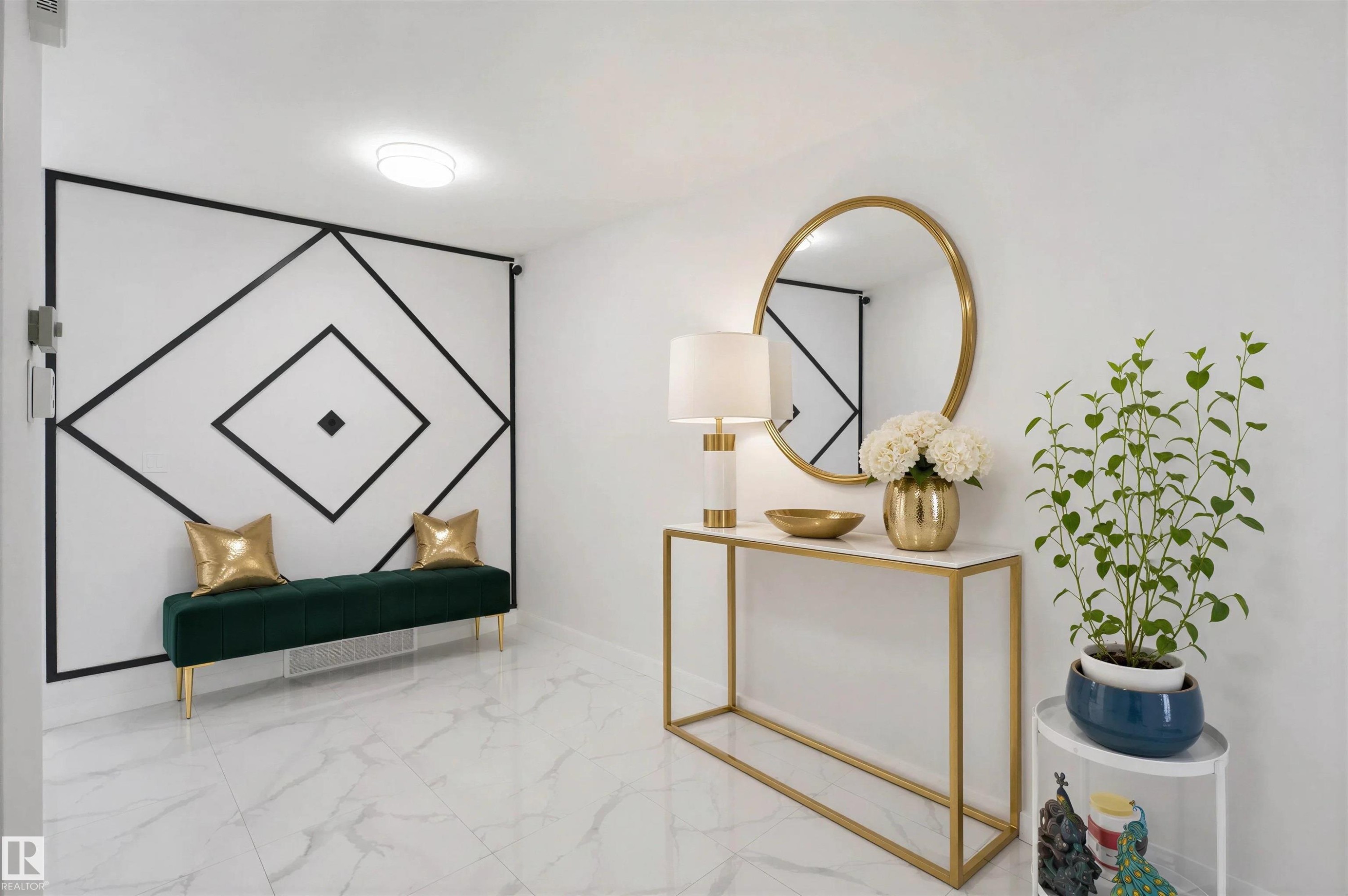 White marble-look flooring, accent wall with geometric molding, recessed ceiling light, and a built-in console table with a gold-framed mirror - 2027 13 Avenue Nw, Edmonton, AB