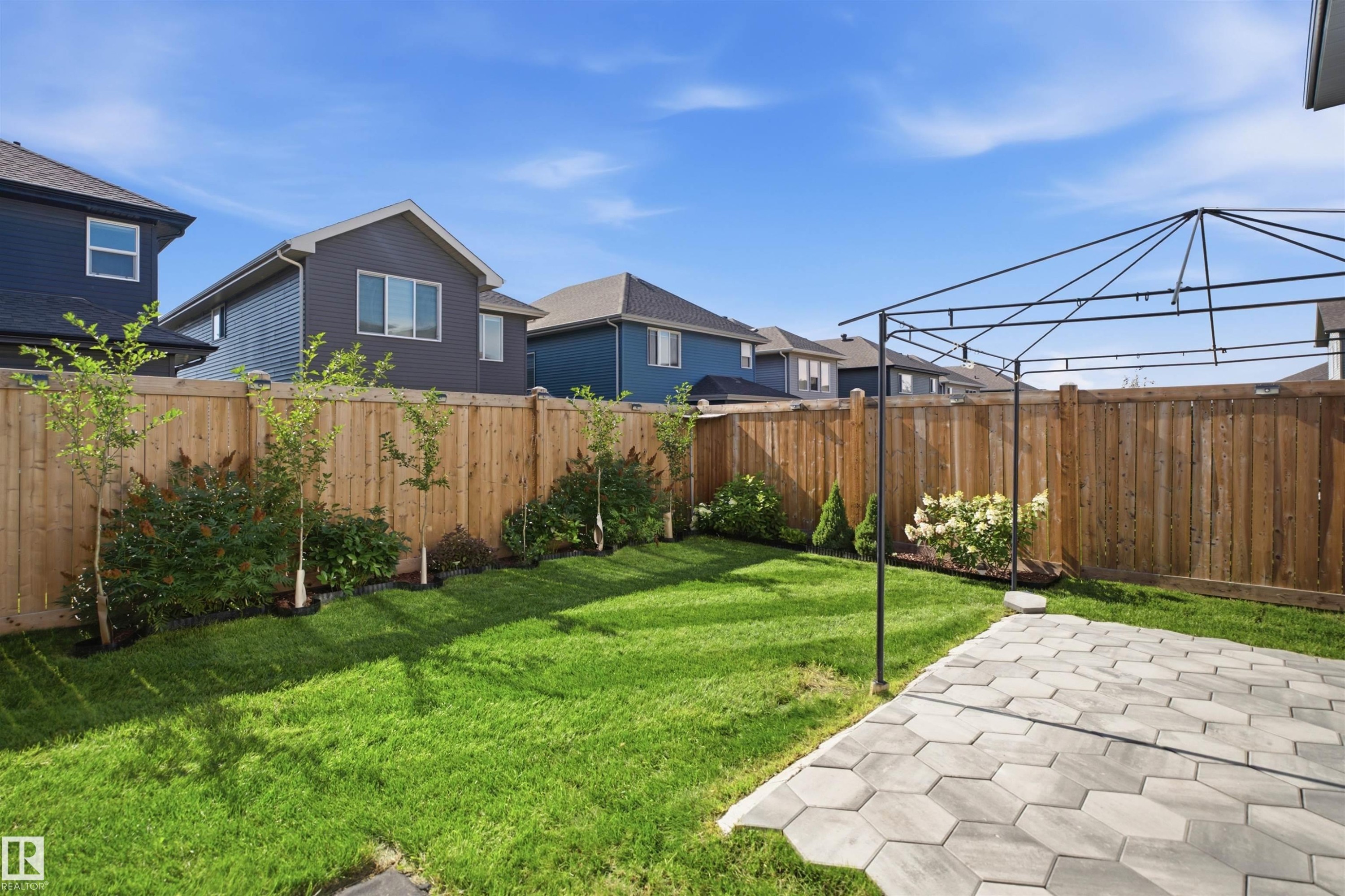 Manicured lawn with a wooden privacy fence, mature landscaping, and a paver patio - 2027 13 Avenue Nw, Edmonton, AB