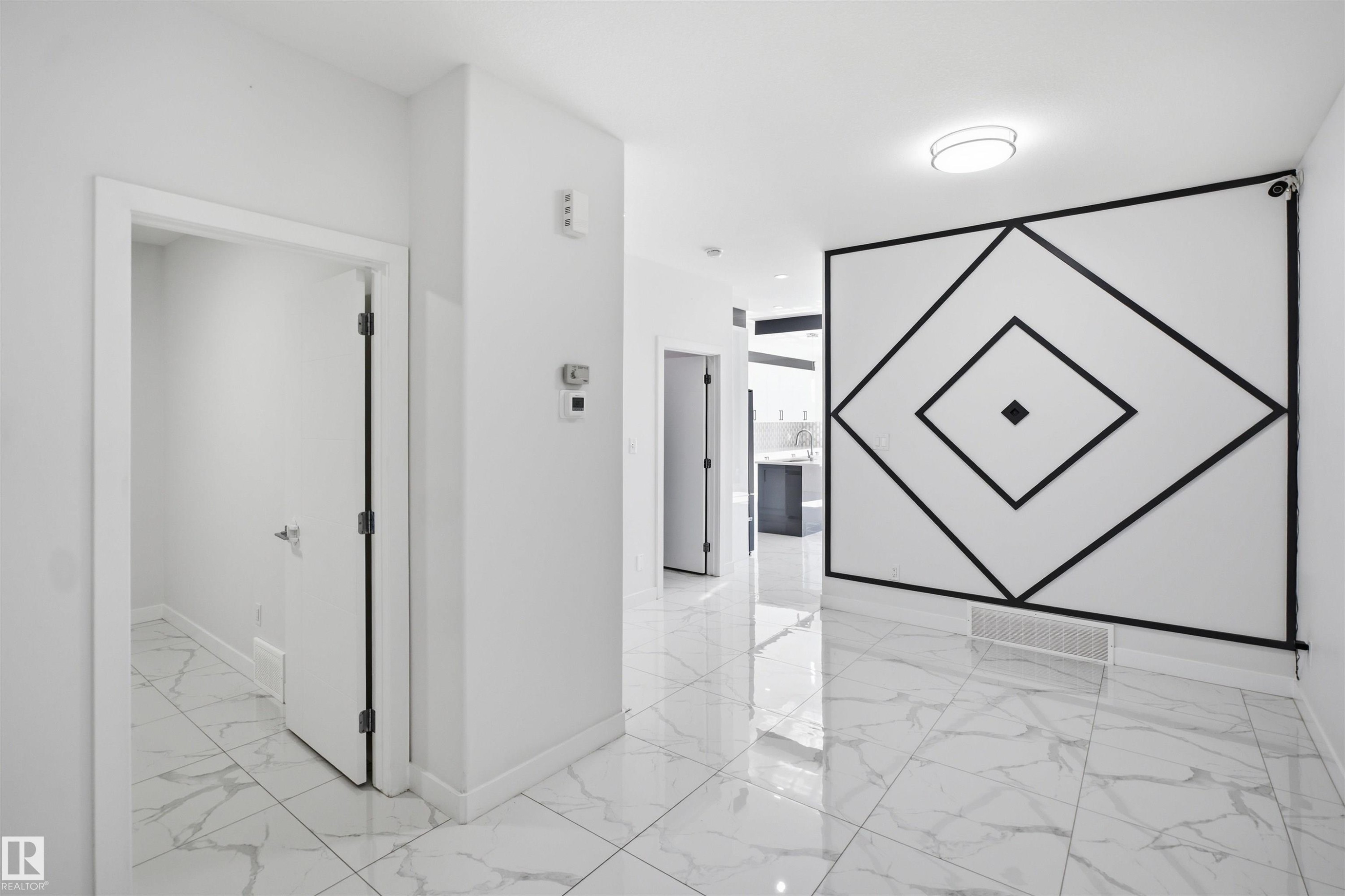 White walls with a black geometric accent, white tile flooring, and a flush-mount ceiling light - 2027 13 Avenue Nw, Edmonton, AB